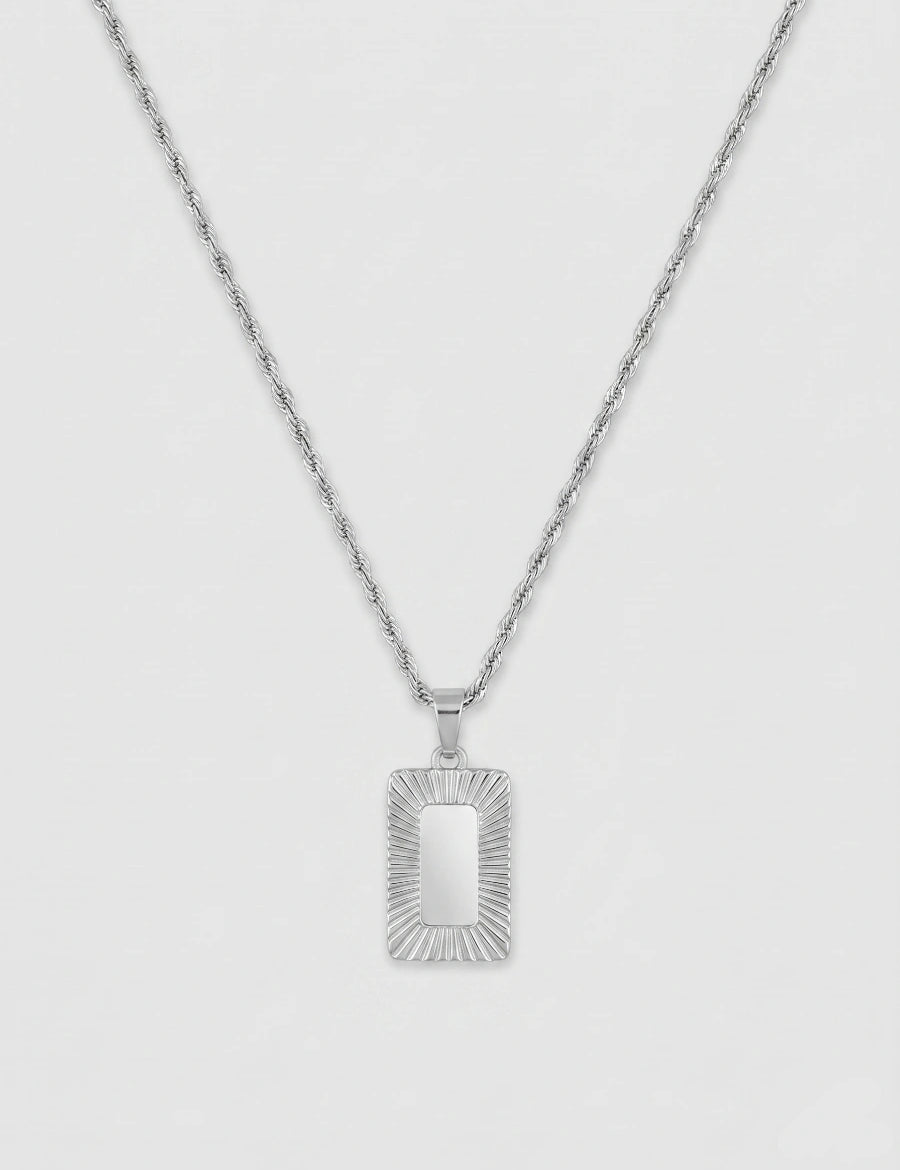 שרשרת גברים בגוון כסף מבריק מסוג חבל שזור (Rope chain) עם תליון מלבני ארכיטקטוני. מרכז התליון חלק ומסגרתו מעוטרת בחריצי עומק רדיאליים המדמים קרני שמש.