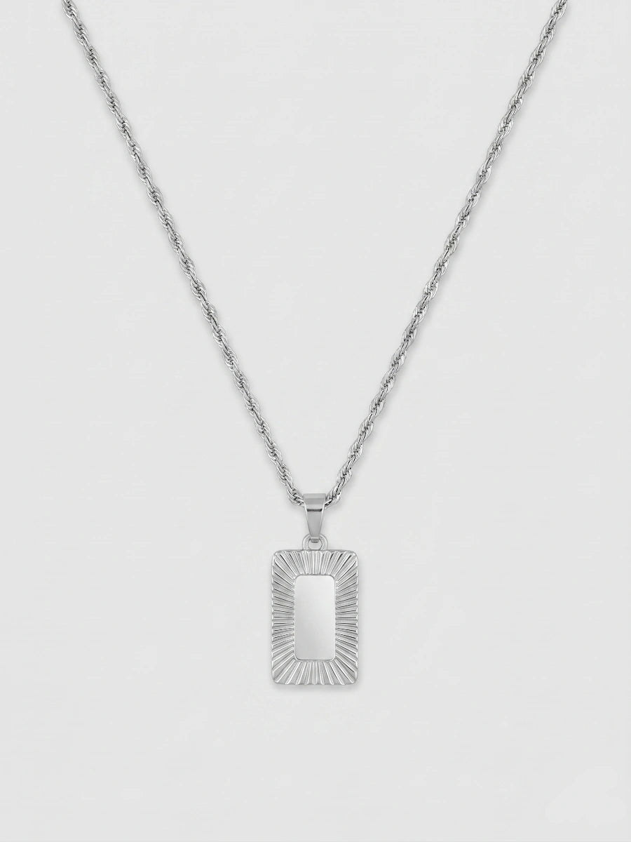 שרשרת גברים בגוון כסף מבריק מסוג חבל שזור (Rope chain) עם תליון מלבני ארכיטקטוני. מרכז התליון חלק ומסגרתו מעוטרת בחריצי עומק רדיאליים המדמים קרני שמש.
