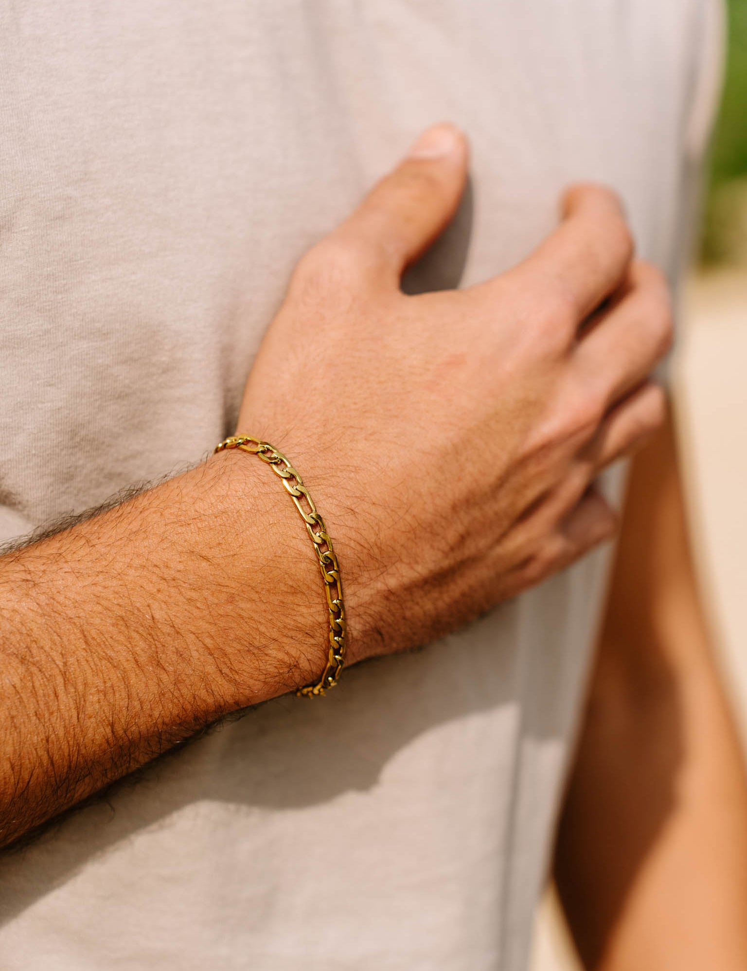 צמיד Apollo של NERO זהב על פרק היד בתנוחת יד על החזה