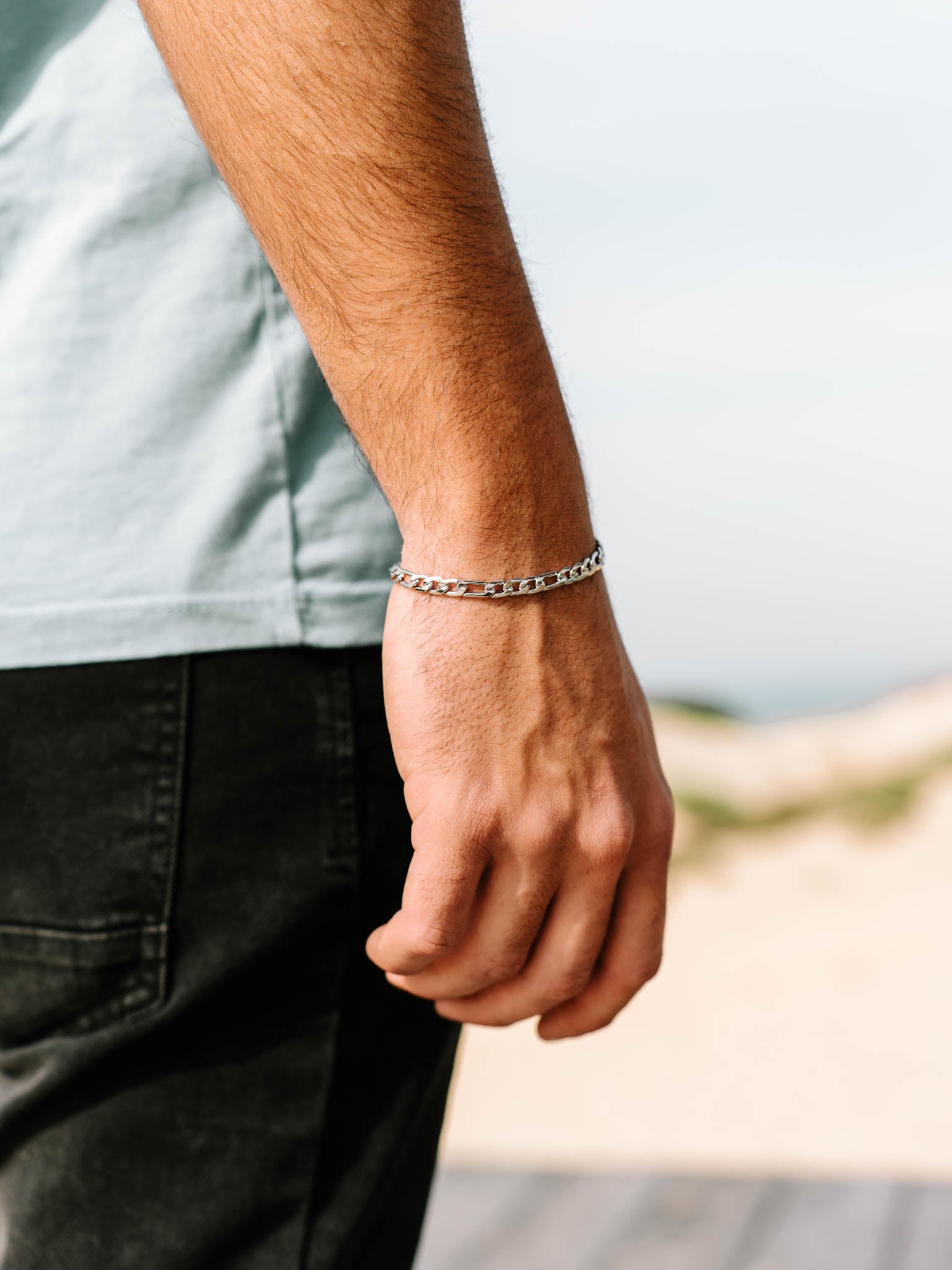 צמיד Apollo של NERO כסף על פרק היד של גבר בצילום חוץ