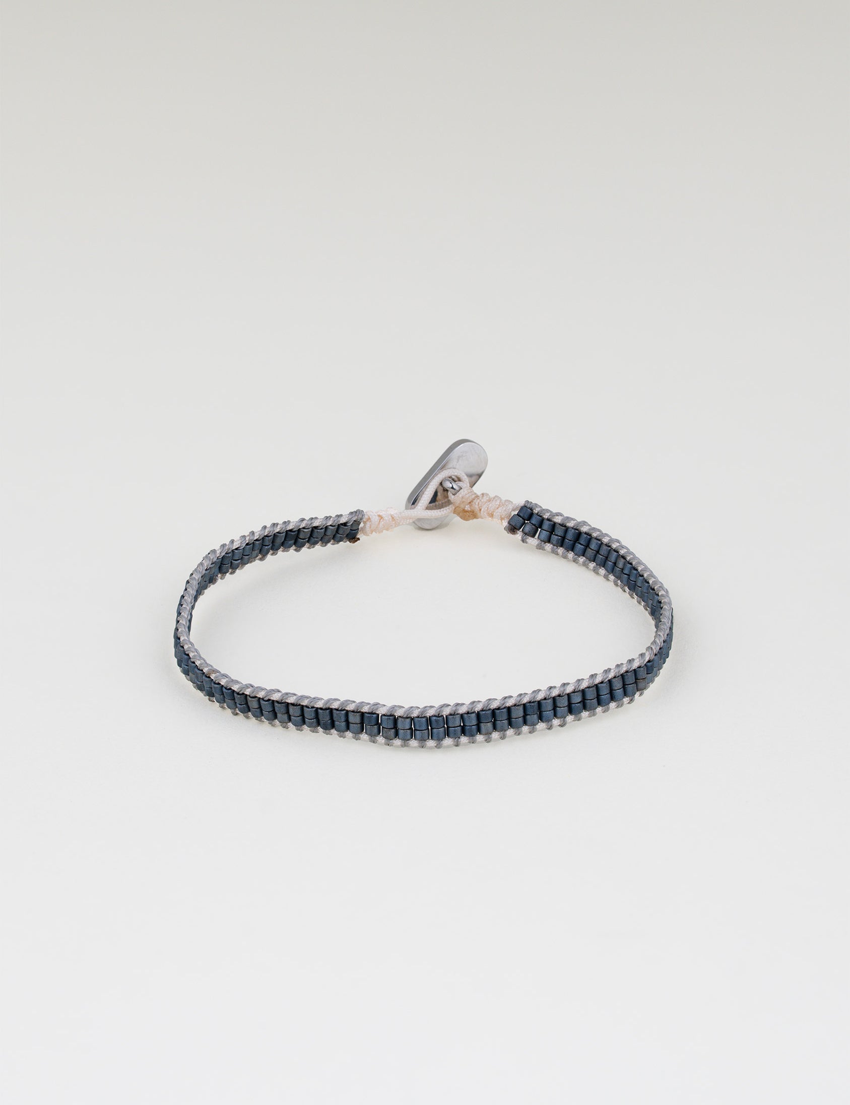 צמיד Aqua כחול כהה (נייבי) עדין, סרוג מחוט בהיר וחרוזים כחולים קטנים, על רקע לבן.