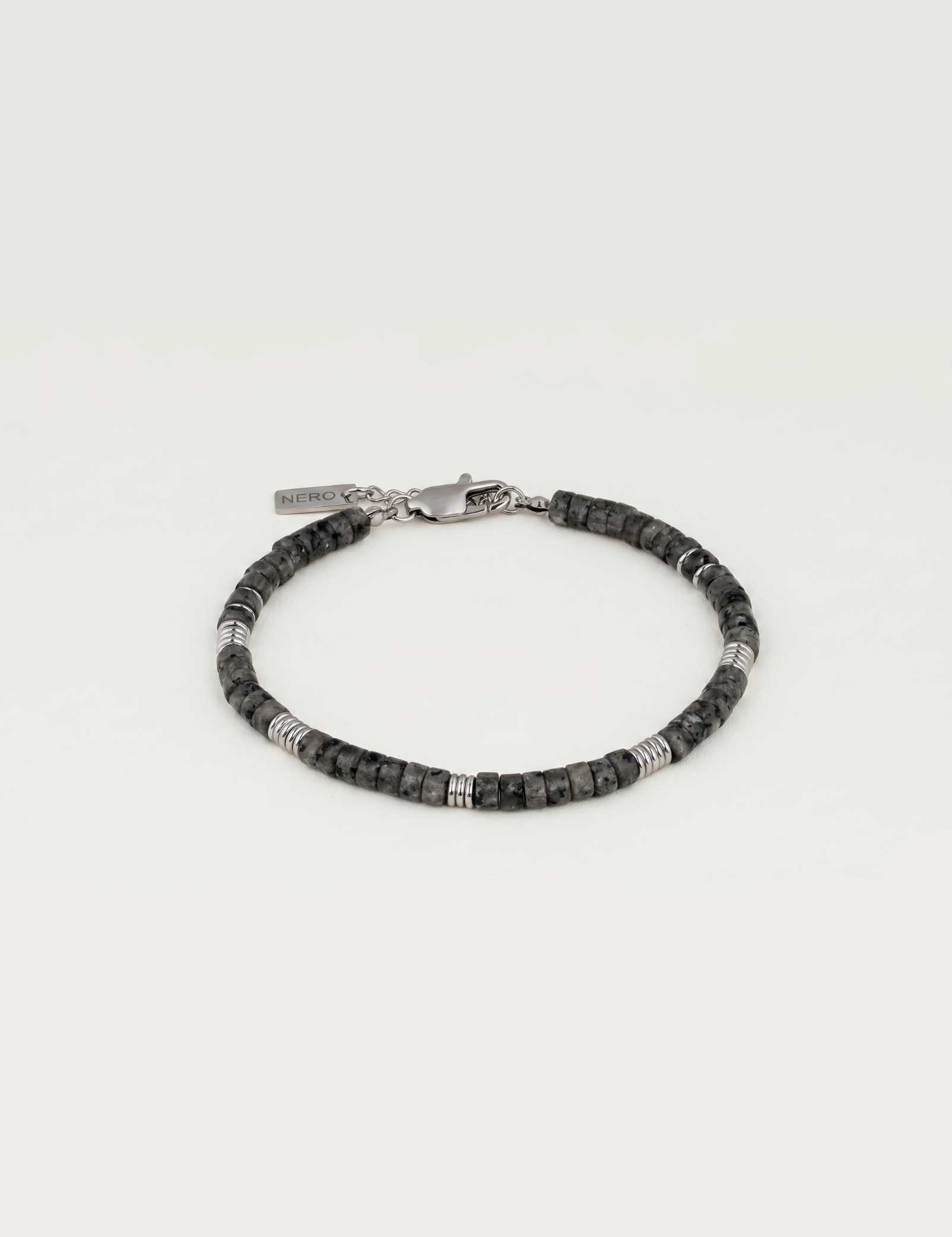 Nero ASH Bracelet from the WILD SPIRIT collection, featuring 4mm matte natural grey-black stones with textured stainless steel spacers and a branded lobster clasp on a clean background.