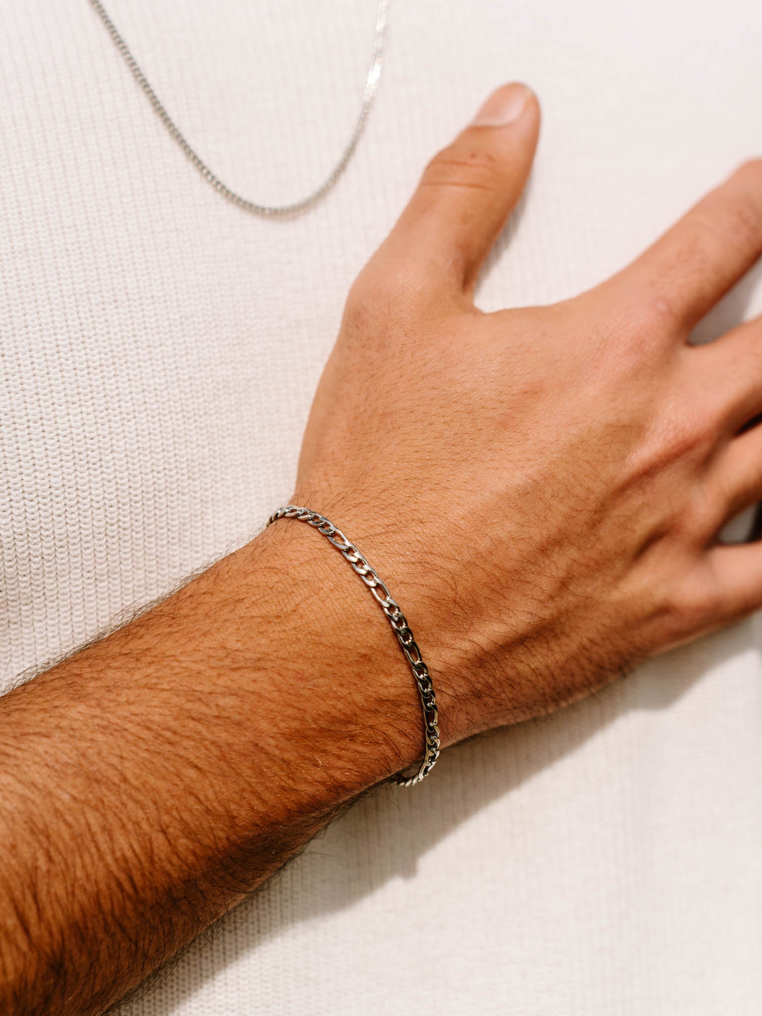 תקריב של צמיד Aura כסף 3.5 מ״מ על פרק היד מעל חולצה לבנה