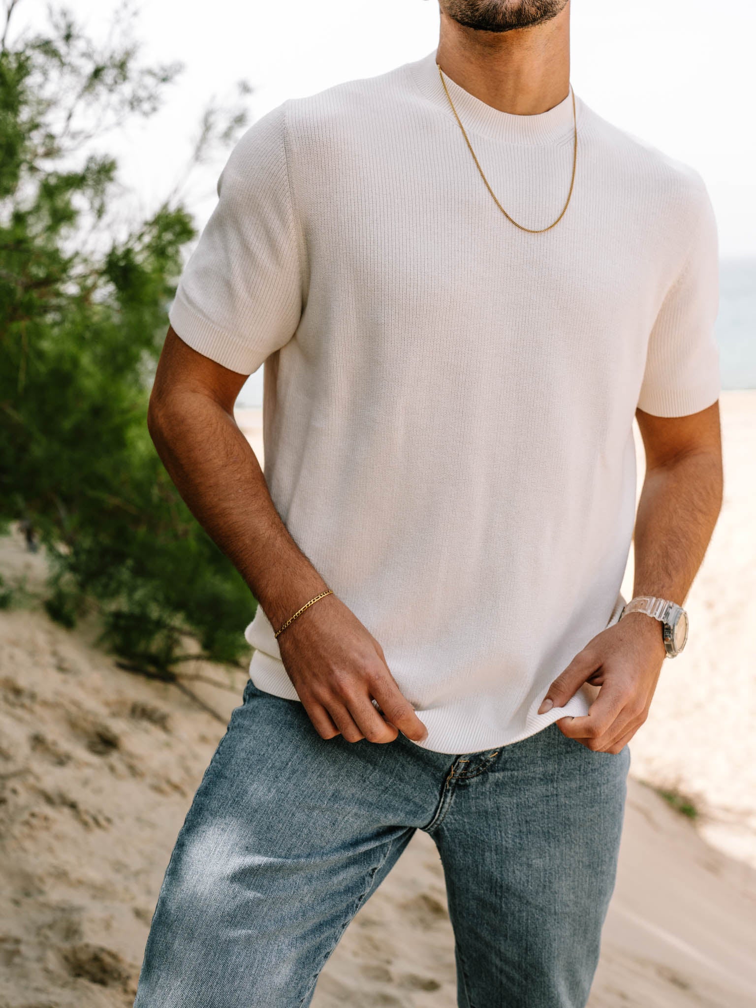 דוגמן לובש סט תכשיטי Aura זהב – צמיד ושרשרת – עם חולצה לבנה ומכנסי ג׳ינס