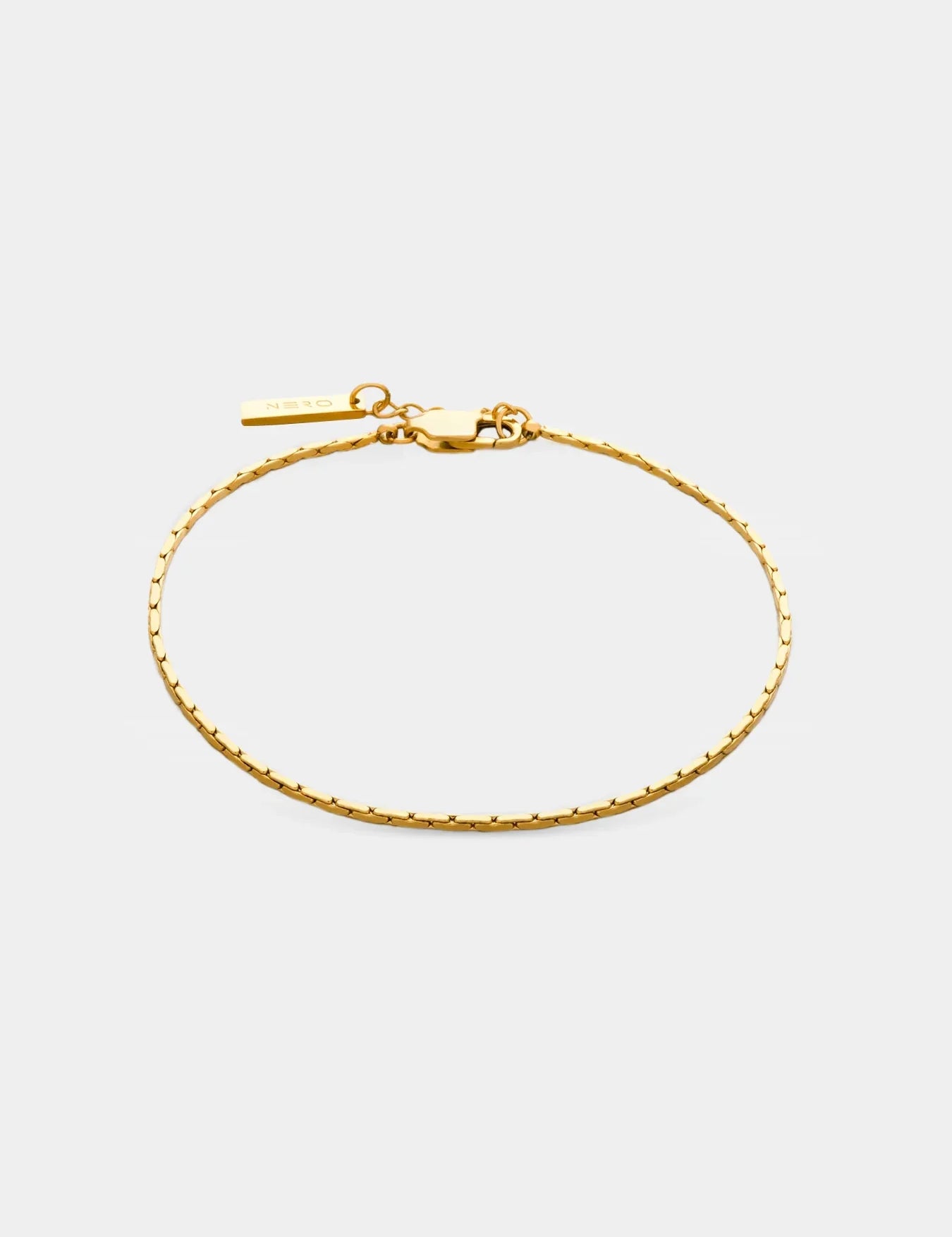 צמיד Barracuda מוזהב דק ומינימליסטי עם תליון קטן של NERO על רקע לבן נקי.