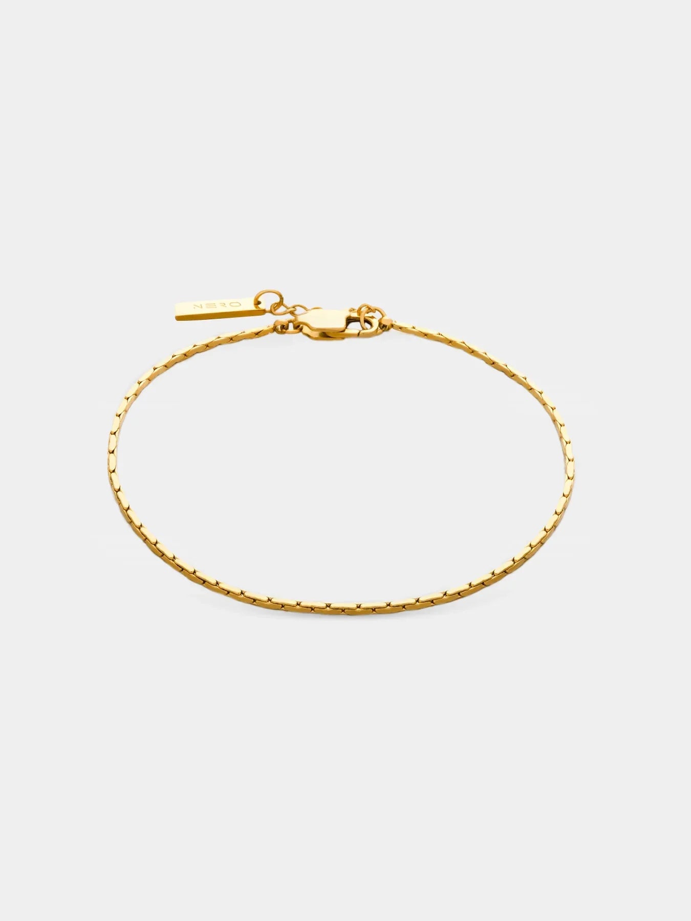 צמיד Barracuda מוזהב דק ומינימליסטי עם תליון קטן של NERO על רקע לבן נקי.