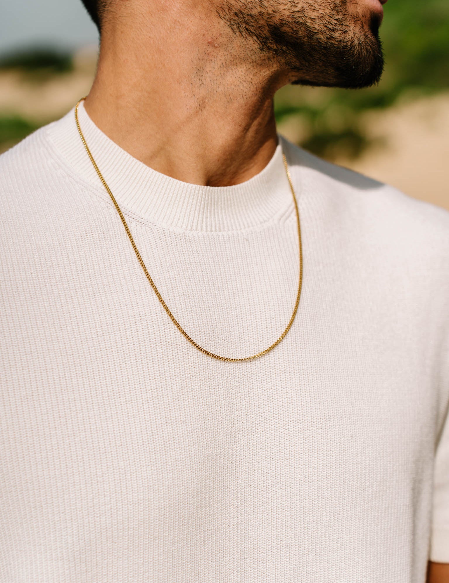 שרשרת Helios זהב על גבר שלובש חולצה לבנה – תכשיט גברי מקולקציית NERO.