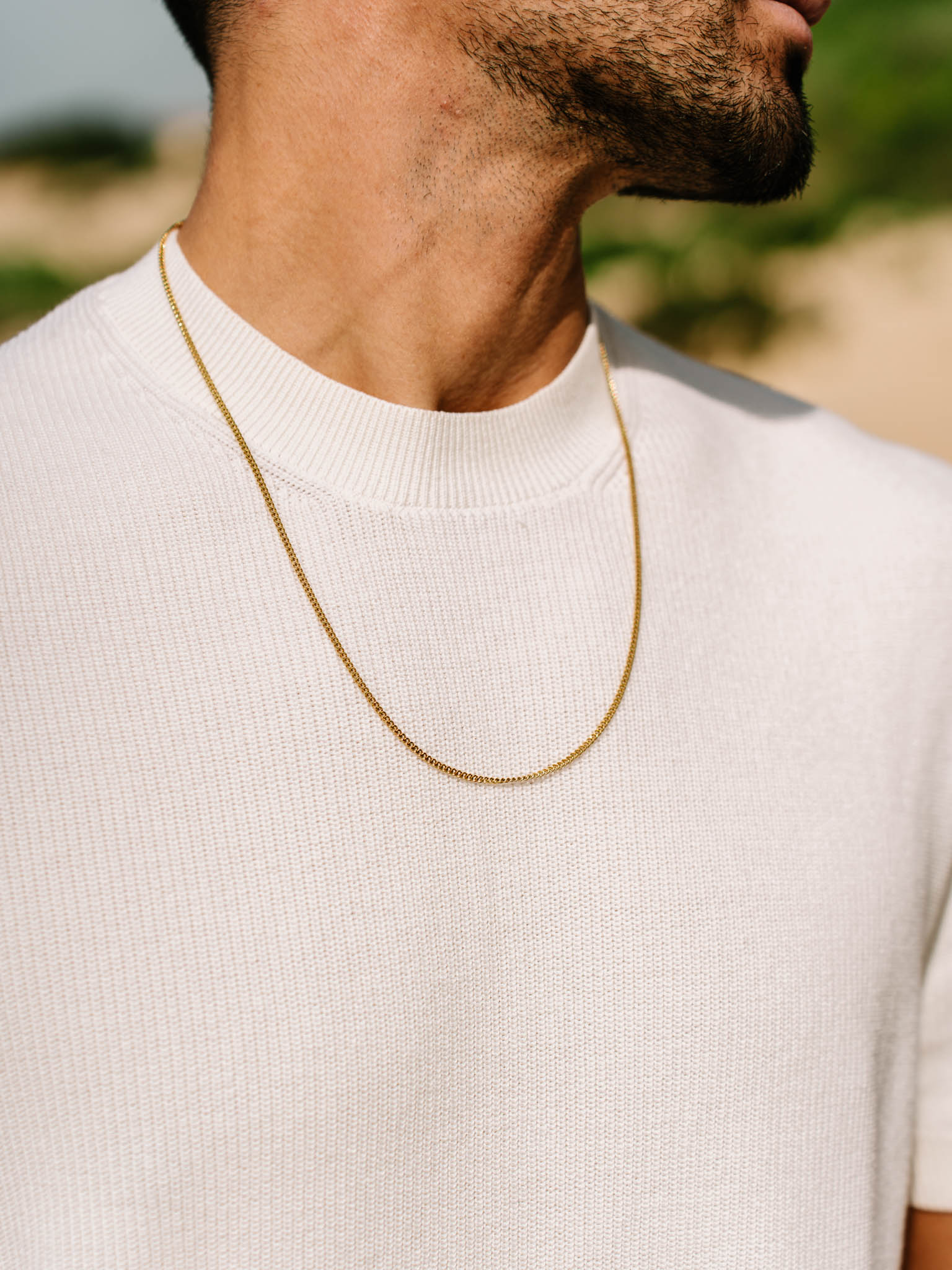 שרשרת Helios זהב על גבר שלובש חולצה לבנה – תכשיט גברי מקולקציית NERO.