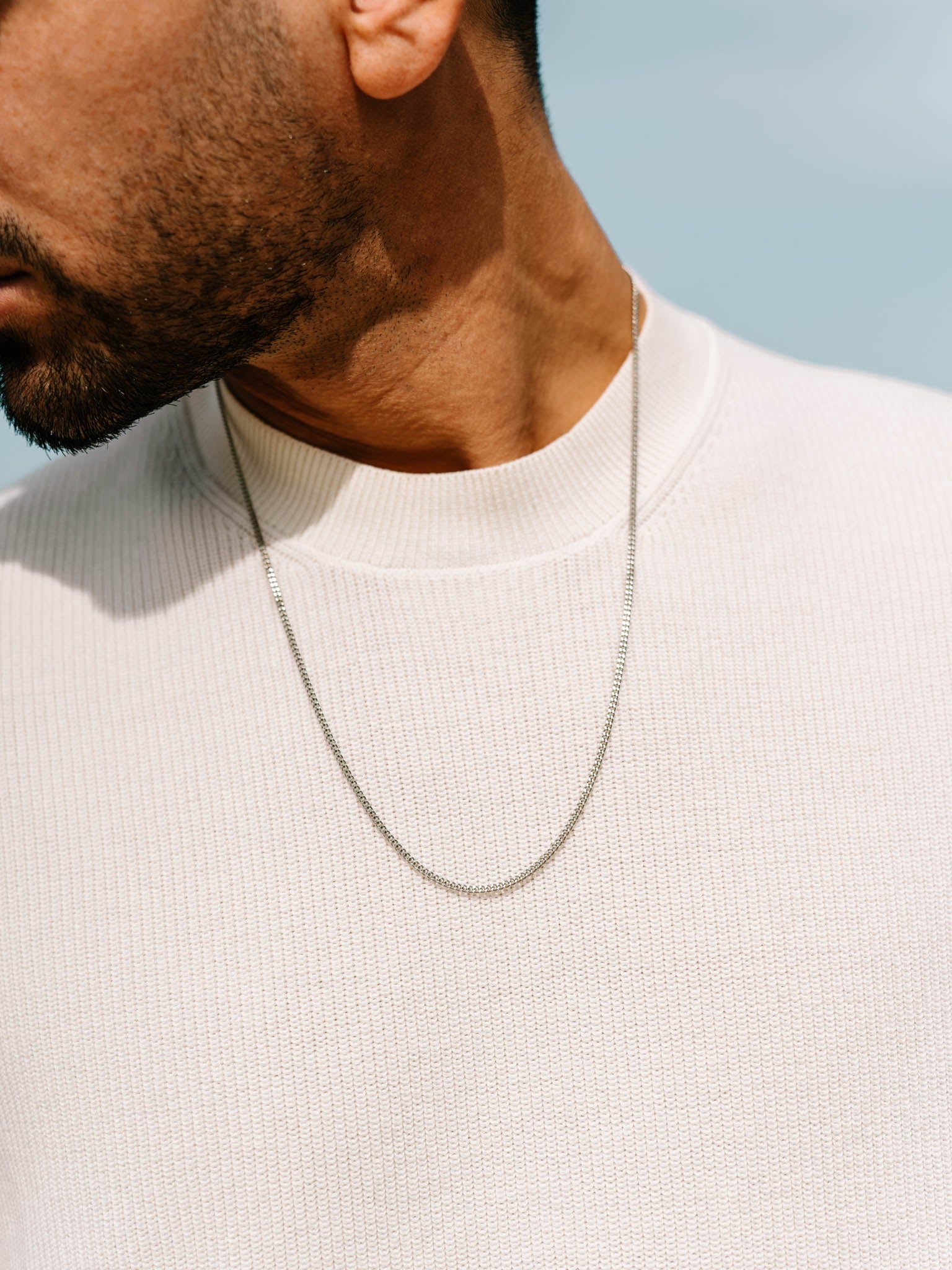 שרשרת Helios בציפוי כסף על גבר שלובש חולצה לבנה – תכשיט גברי של NERO.
