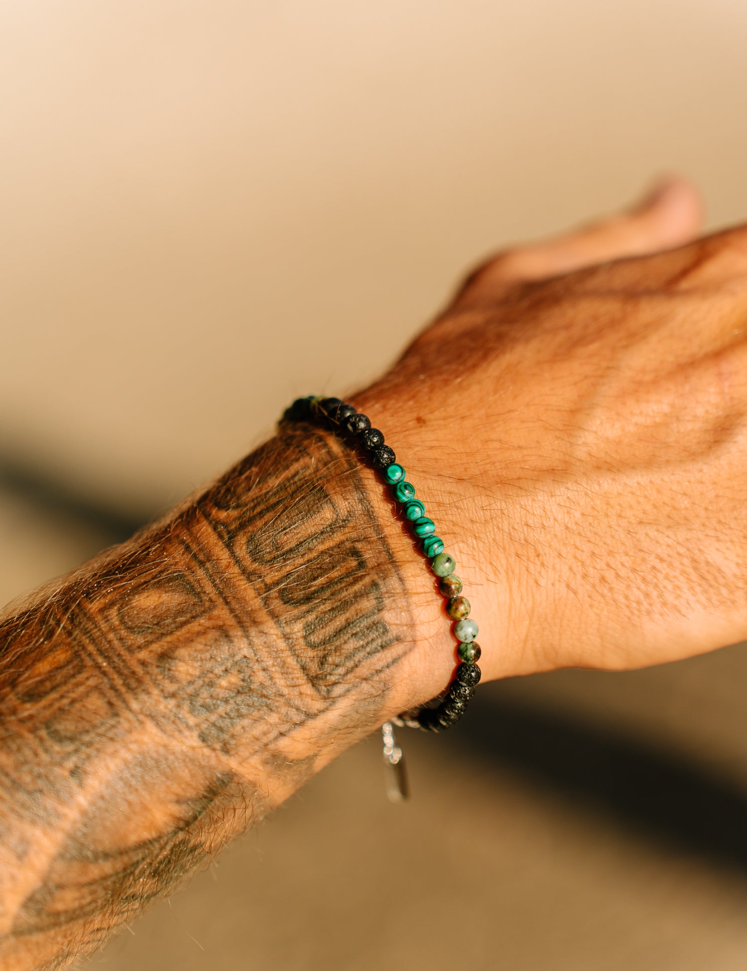 צמיד Kai (מלכיט ולבה) משולב עם שרשראות וטבעת Ocean Gems, בסטיילינג חוף.