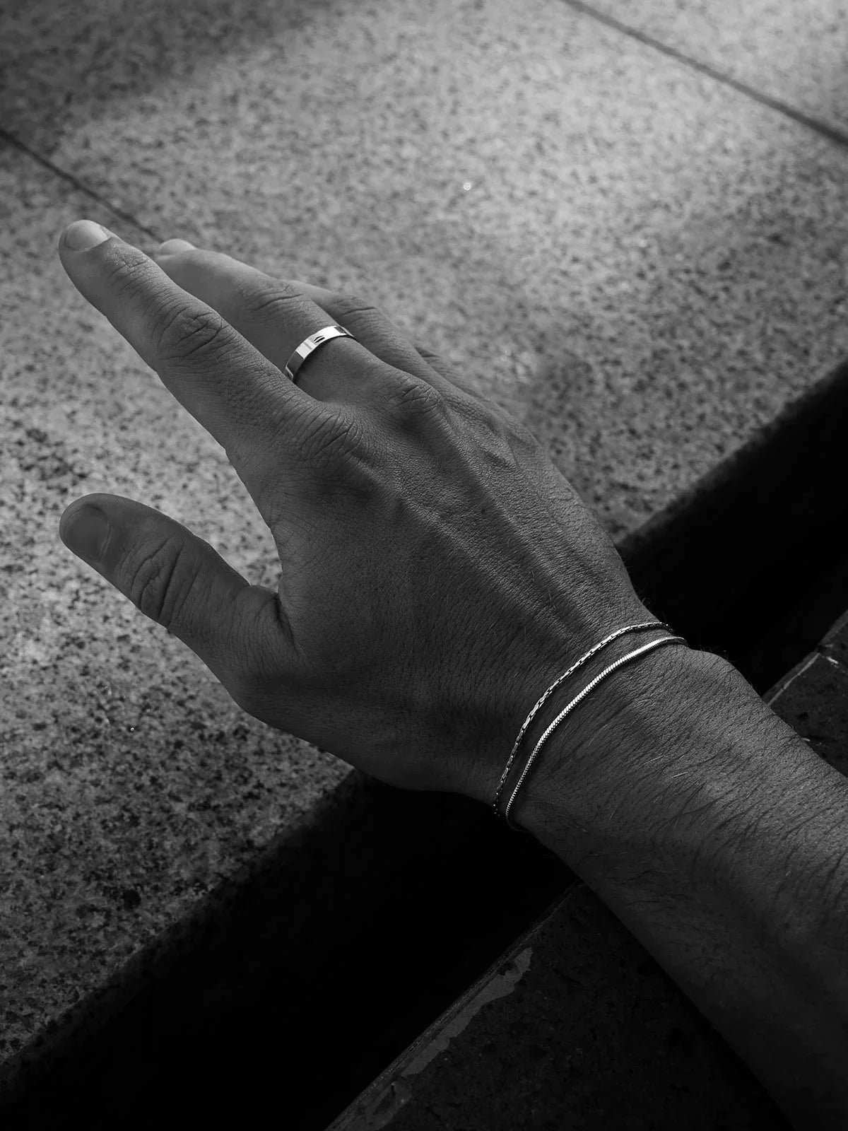 צמיד Manta לגבר בגימור כסוף בצילום לייף סטייל שחור־לבן על פרק כף היד