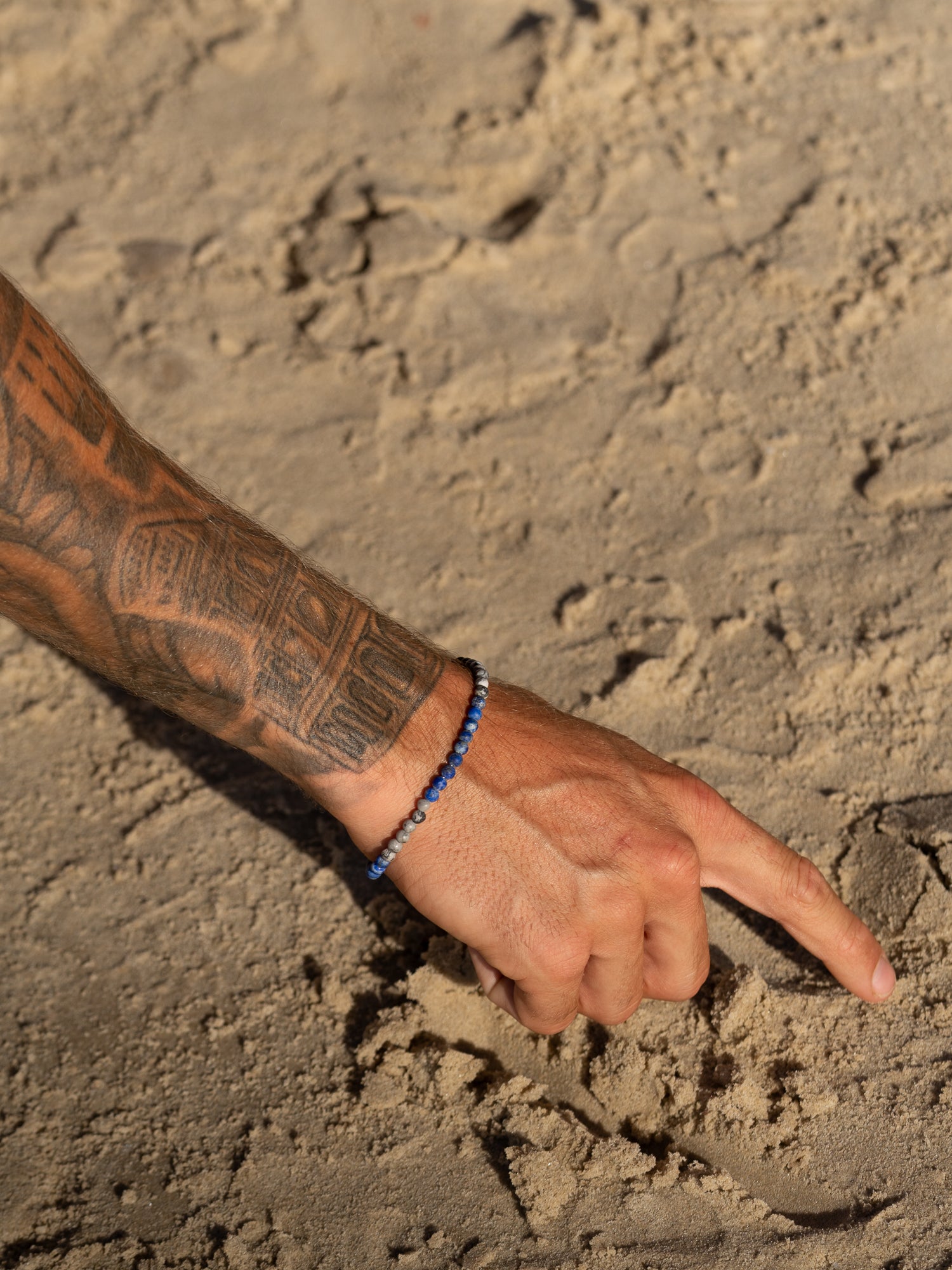 צמיד Marine (לפיס וג'ספר מט) על פרק יד גברי, צילום תקריב המדגיש את צבעי הים העמוק.