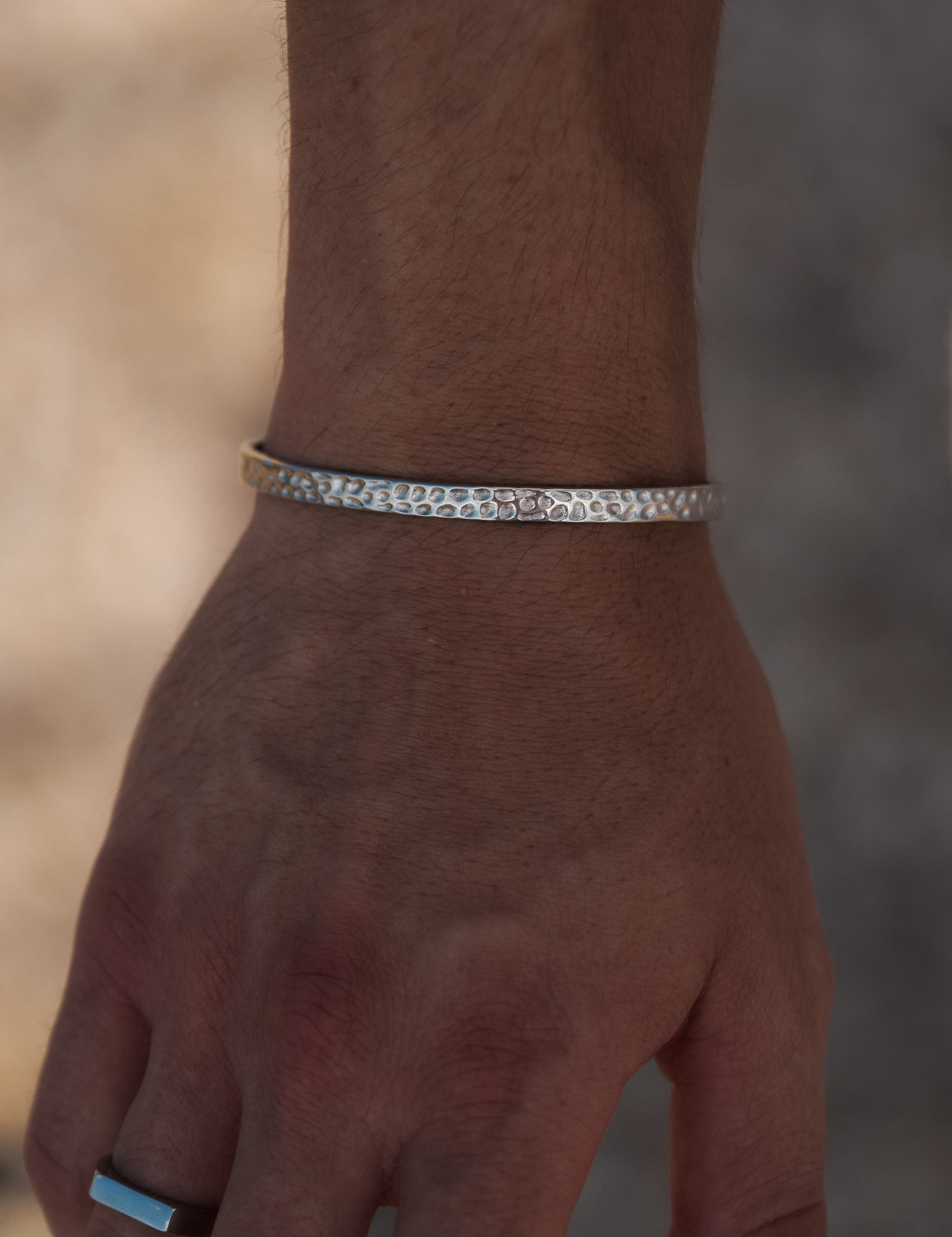 צמיד Meduza לגבר בצבע כסף עם טקסטורה מחוררת עדינה, על פרק כף היד.