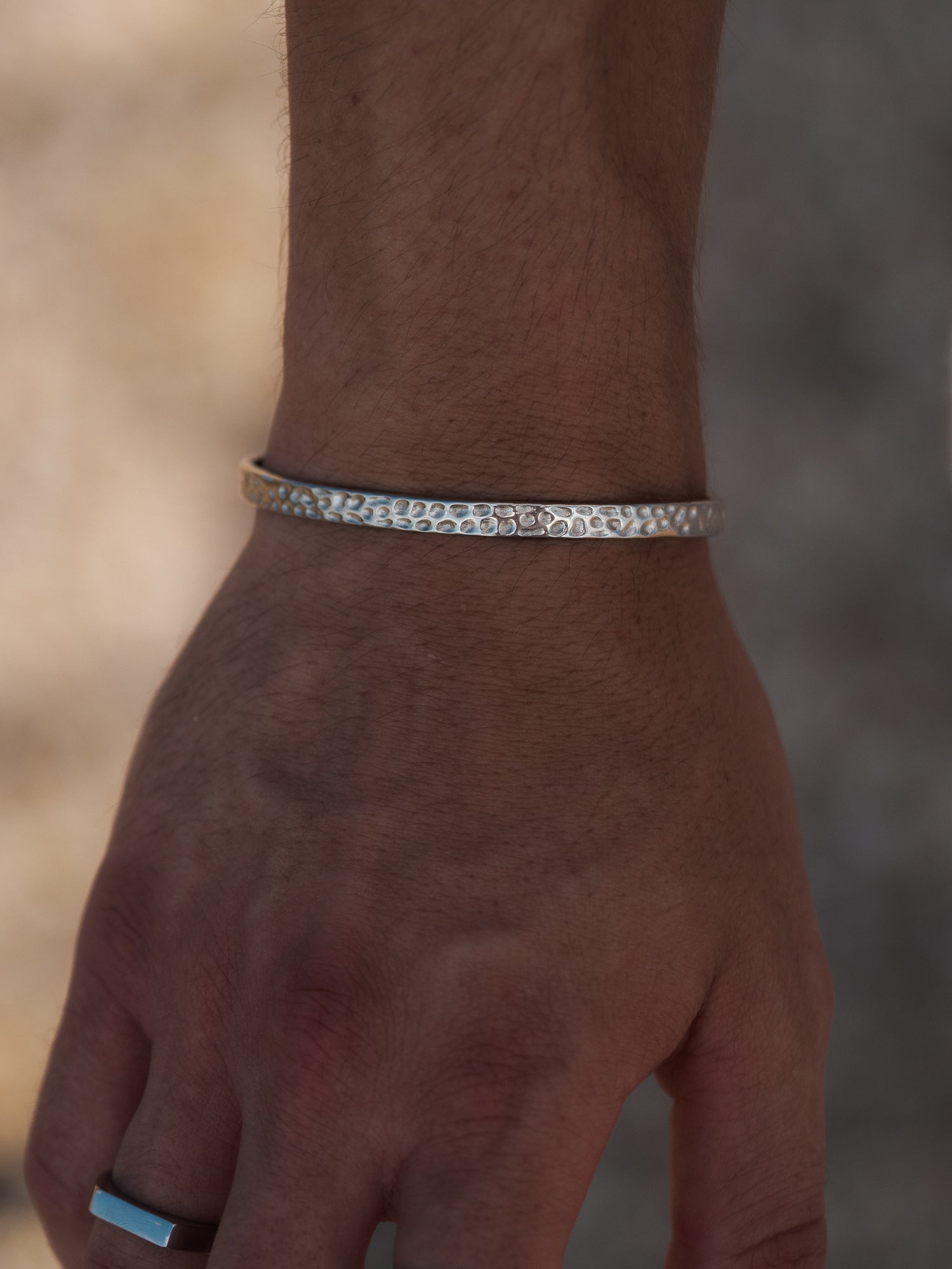 צמיד Meduza לגבר בצבע כסף עם טקסטורה מחוררת עדינה, על פרק כף היד.