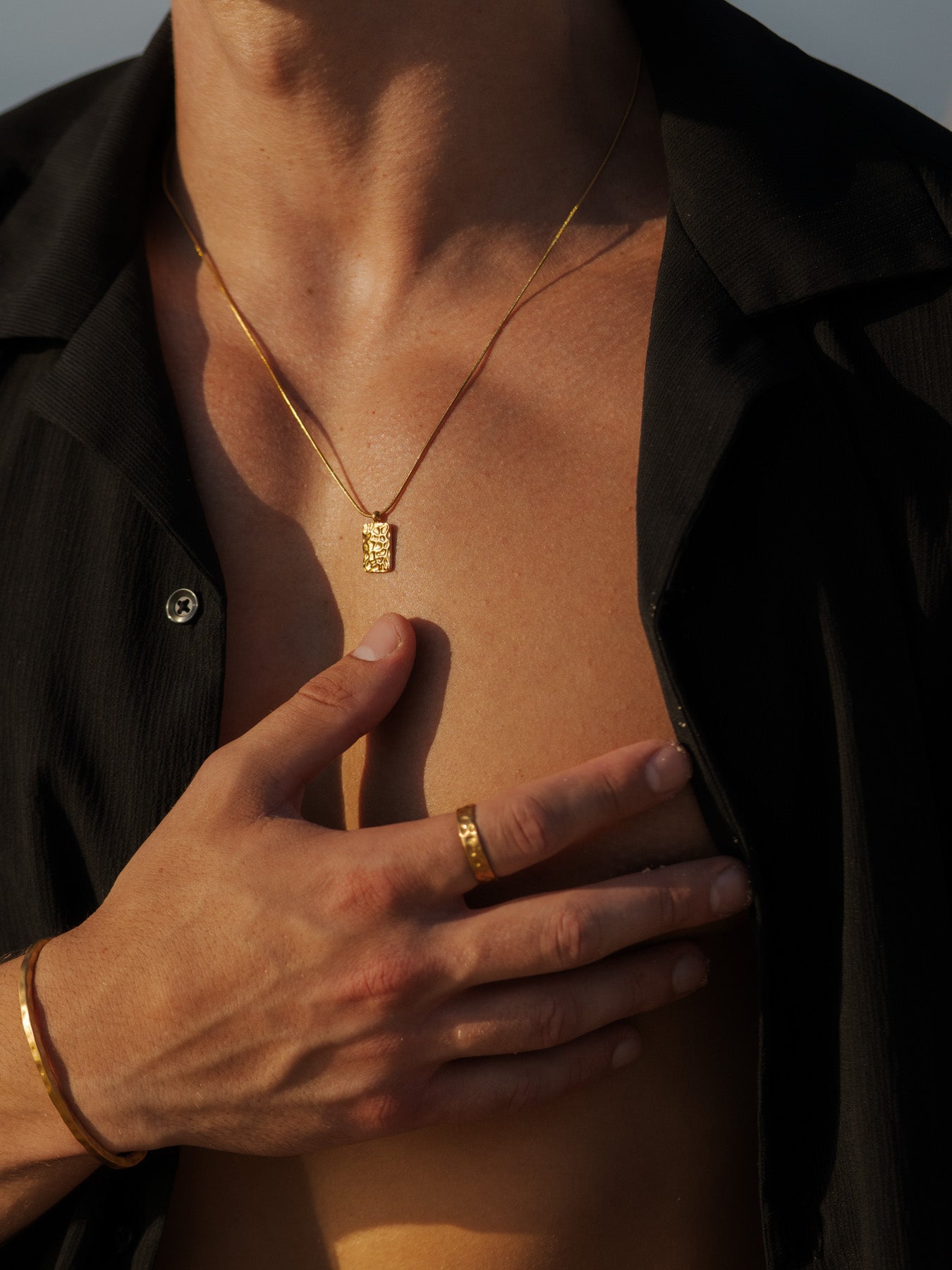 שרשרת Meduza זהב ותליון מבריק, מעוצבת על דגם עם חולצה שחורה.