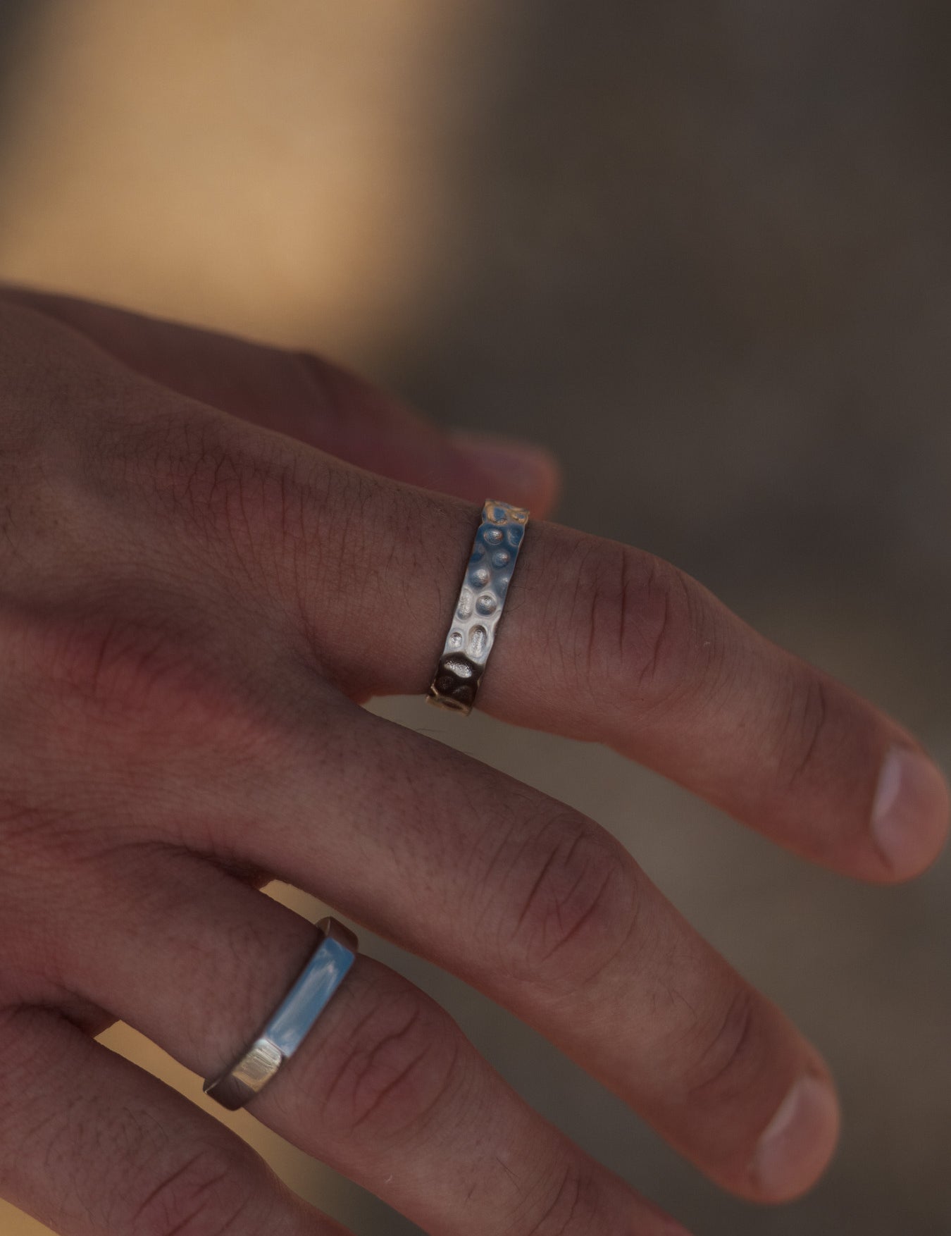 טבעת Meduza כסף לגבר בגימור מט יחד עם צמיד כסף, על רקע סלע חוף.