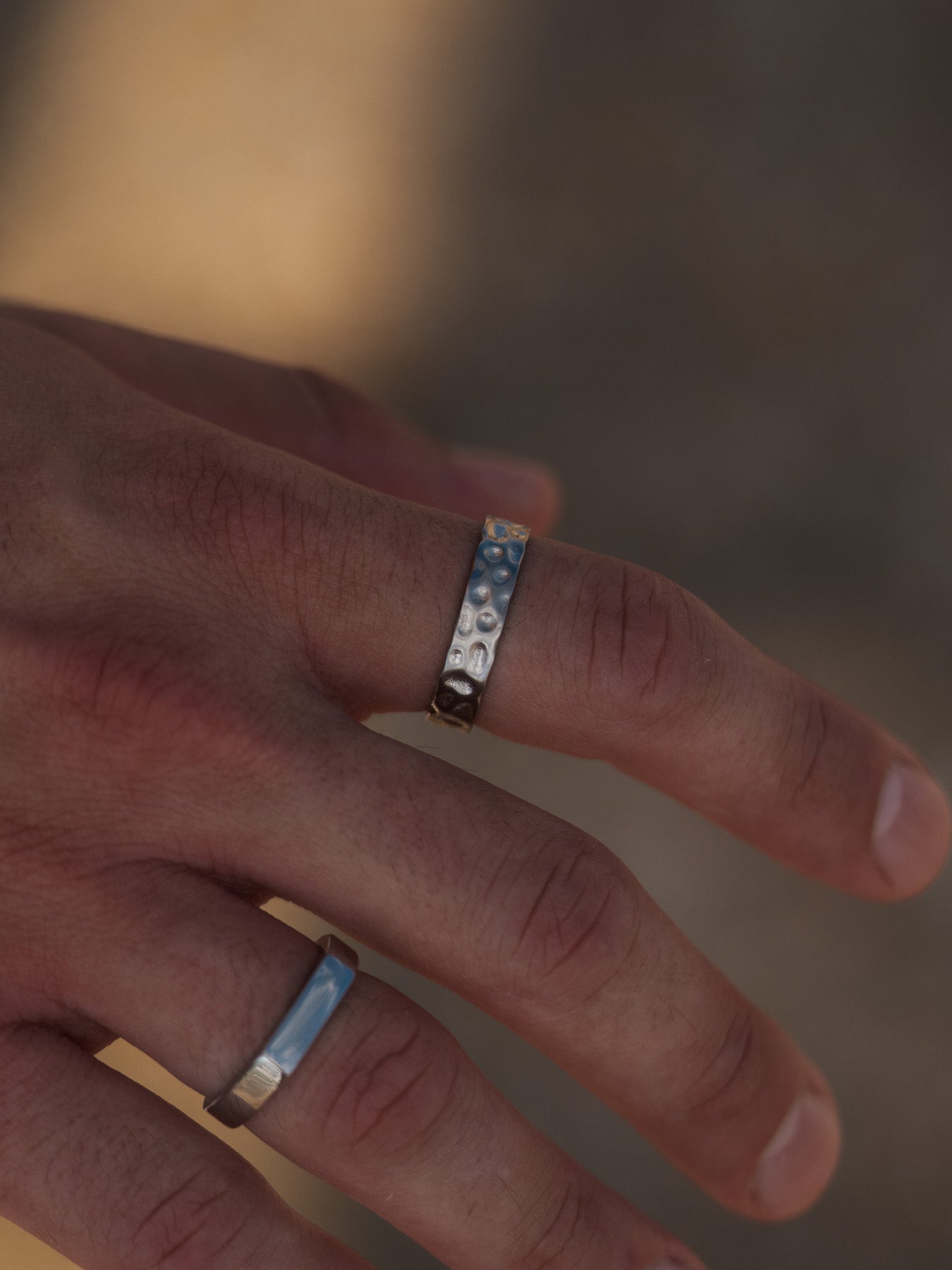 טבעת Meduza כסף לגבר בגימור מט יחד עם צמיד כסף, על רקע סלע חוף.