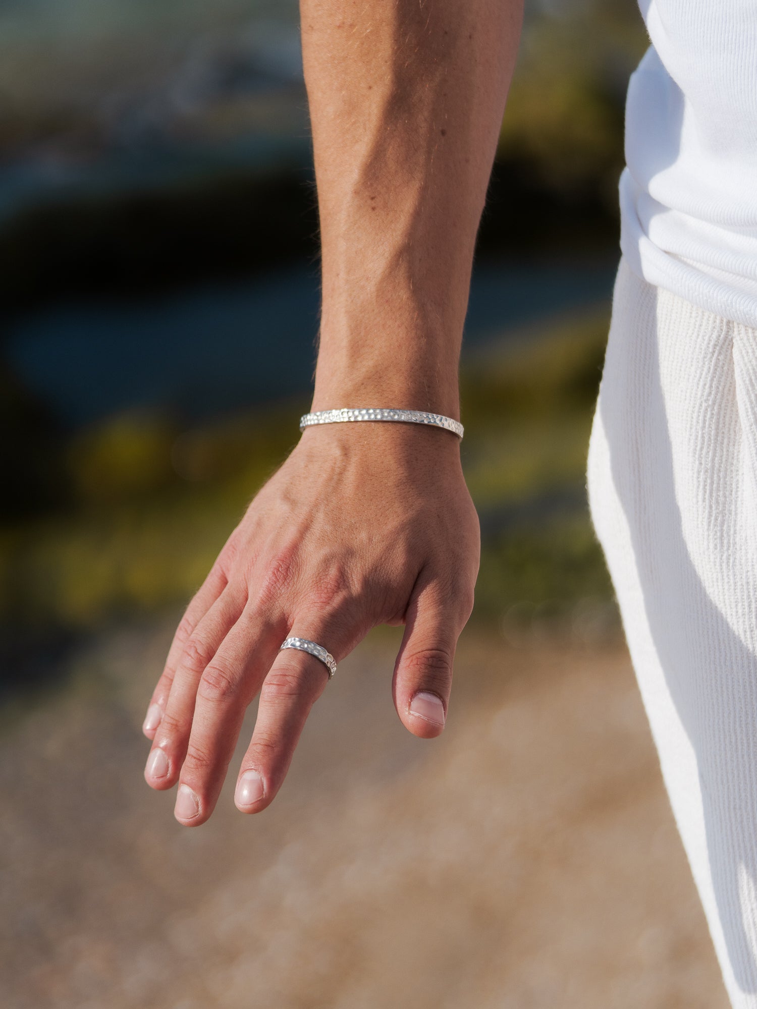 טבעת Meduza כסף לגבר בגימור מט, צילום תקריב על יד גברית במים.