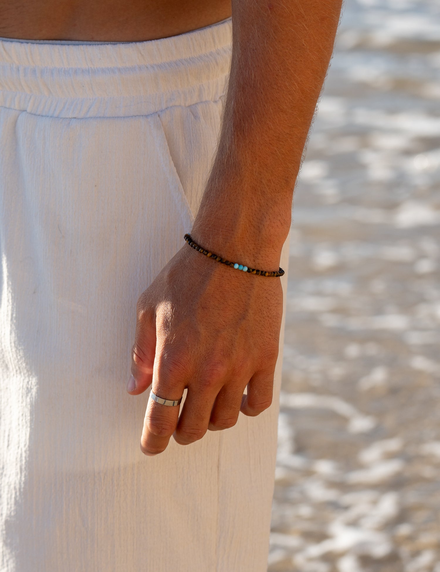 צמיד Mistral לגבר משולב עם שרשרת ותכשיטים נוספים, בסטיילינג חוף על חזה גברי.