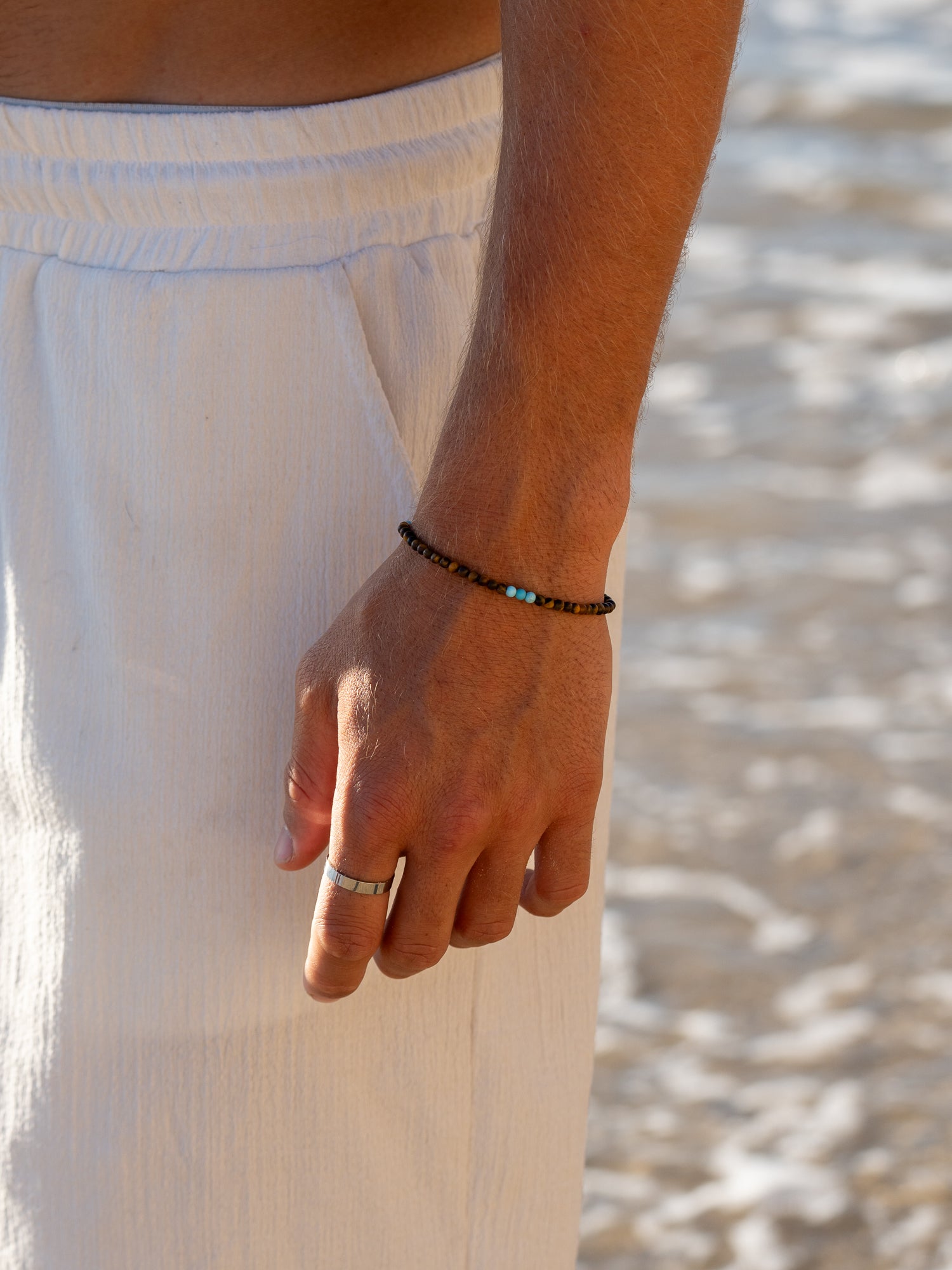 צמיד Mistral לגבר משולב עם שרשרת ותכשיטים נוספים, בסטיילינג חוף על חזה גברי.