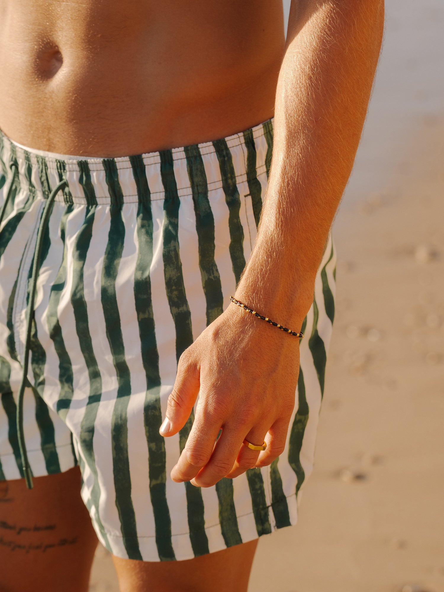 צמיד Moonstone זהב (חוט שעווה) על פרק יד גברי, בסטיילינג עדין, צילום תקריב.