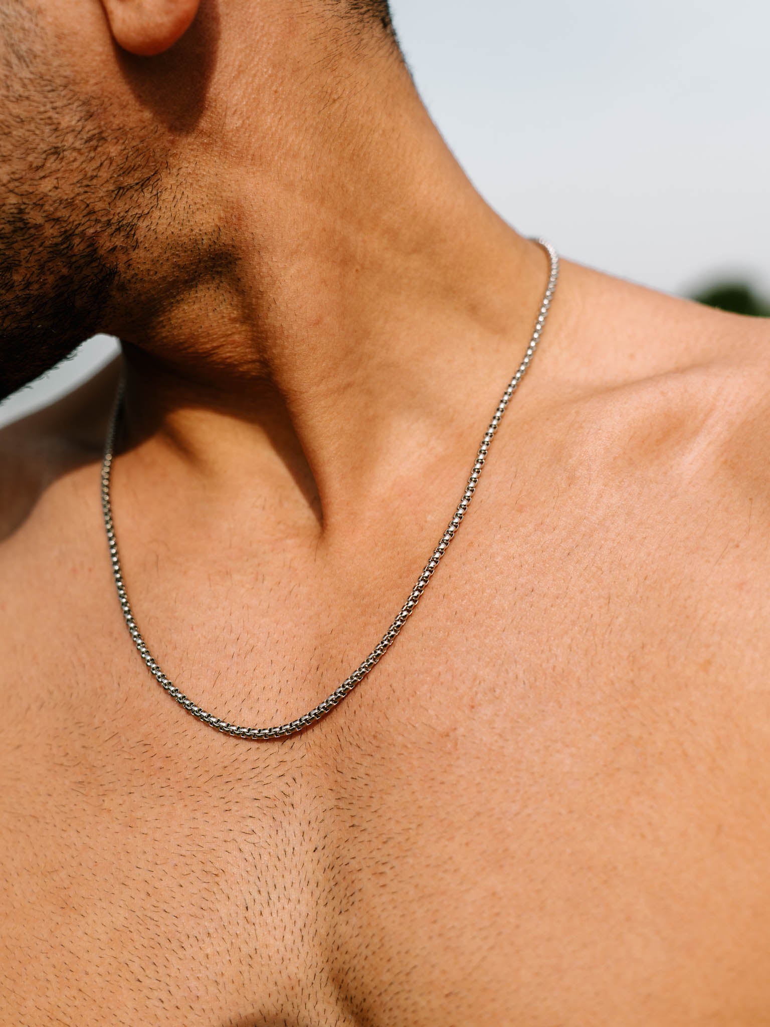 שרשרת Neptune כסף על צוואר של גבר ללא חולצה, צילום תקריב.