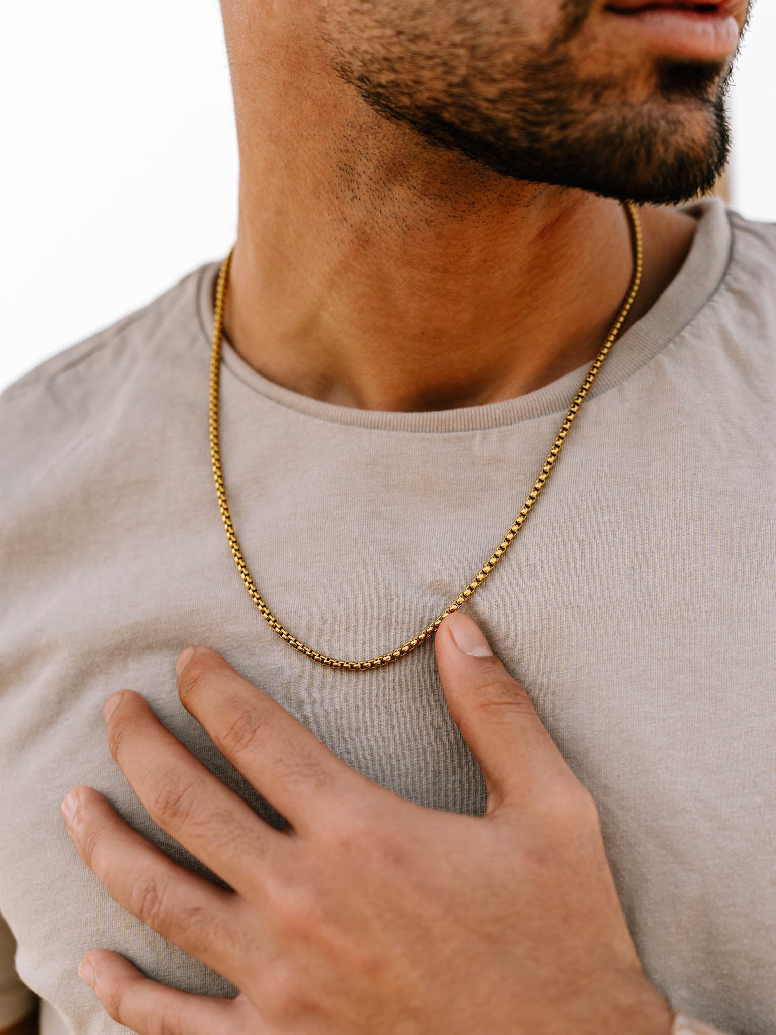 שרשרת Neptune זהב על צוואר של גבר בטופ בהיר, צילום תקריב.