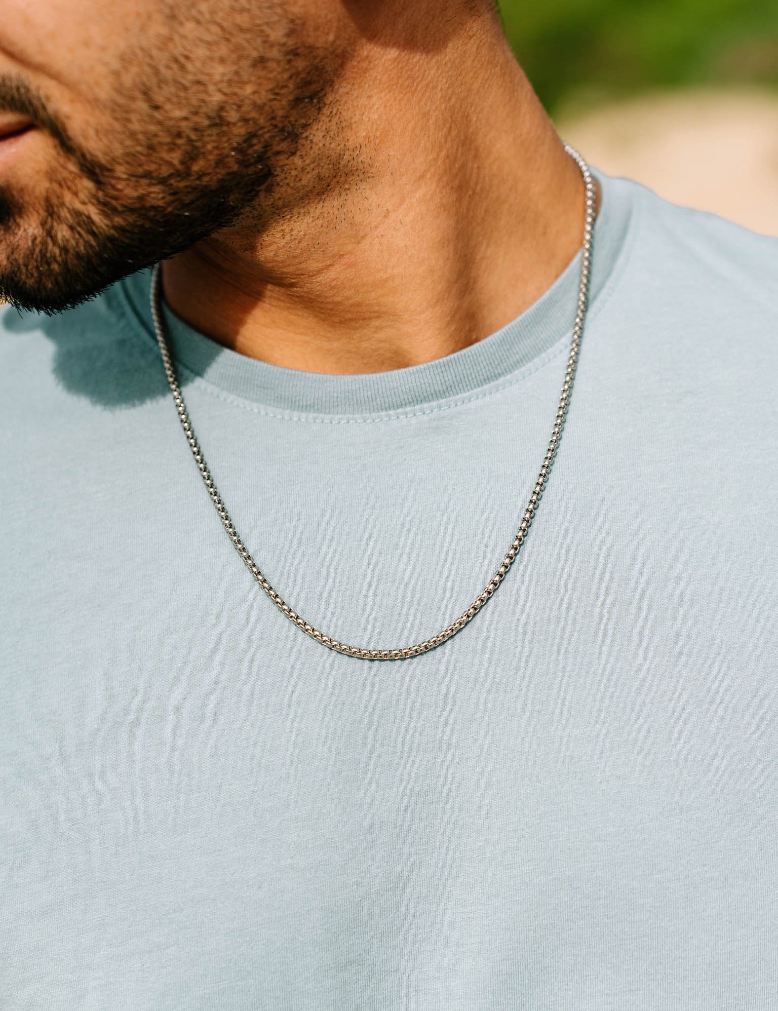 שרשרת Neptune כסף על גבר בטי שירט בהירה, צילום תקריב.