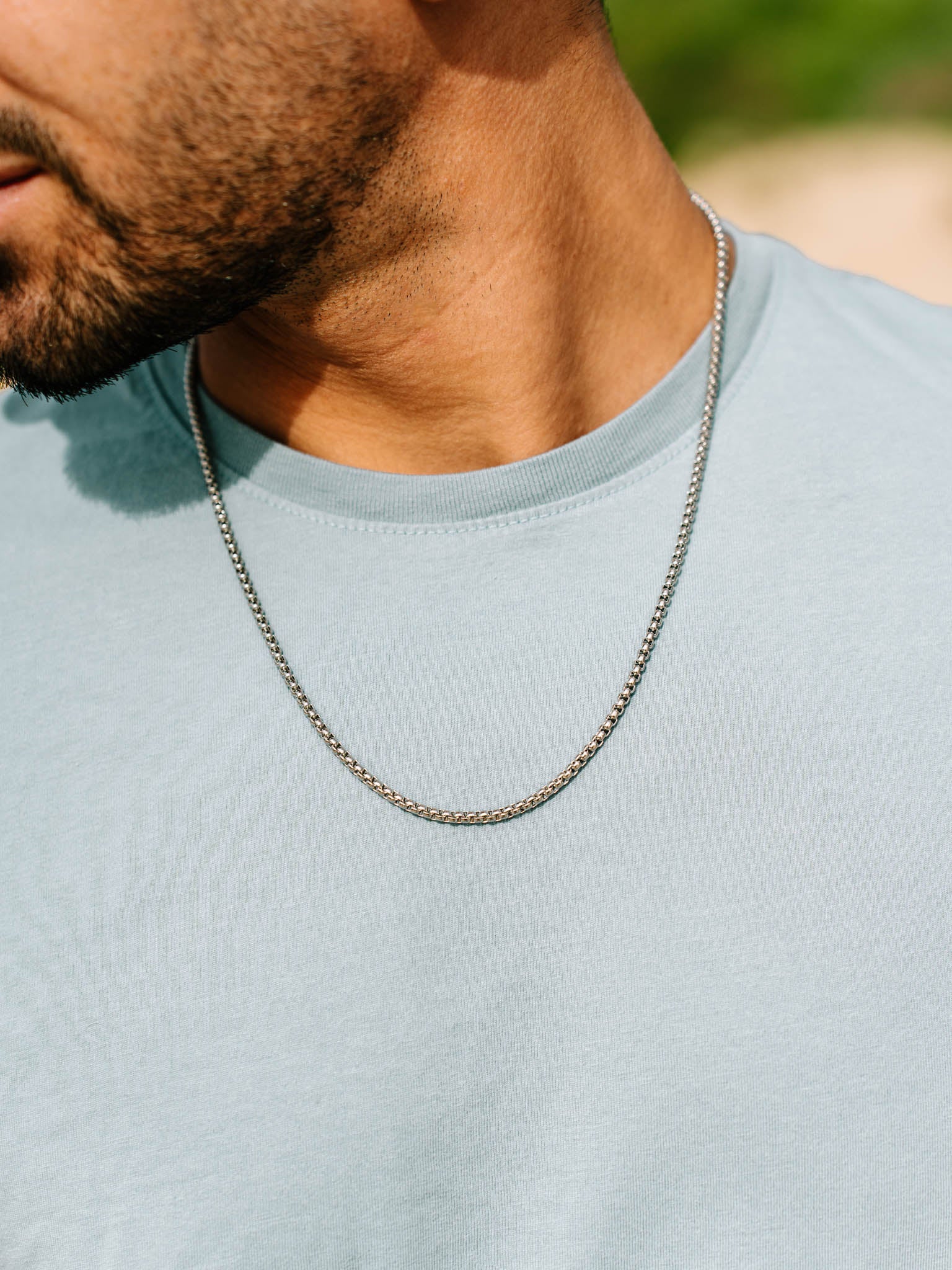 שרשרת Neptune כסף על גבר בטי שירט בהירה, צילום תקריב.