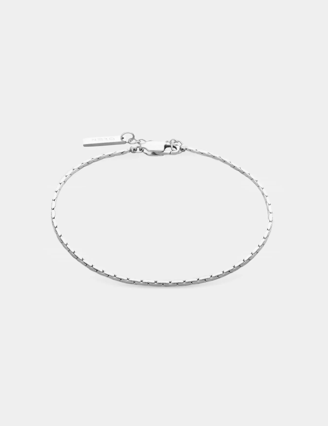 צמיד Barracuda דק בציפוי כסף על רקע לבן, עם תליון NERO קטן ליד הסוגר