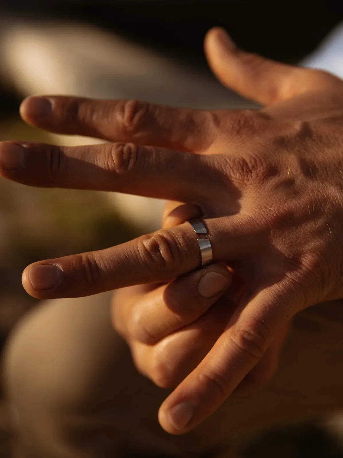 יד של גבר עם טבעת Oyster כסופה בגימור מט – NERO, צילום בתאורת שקיעה