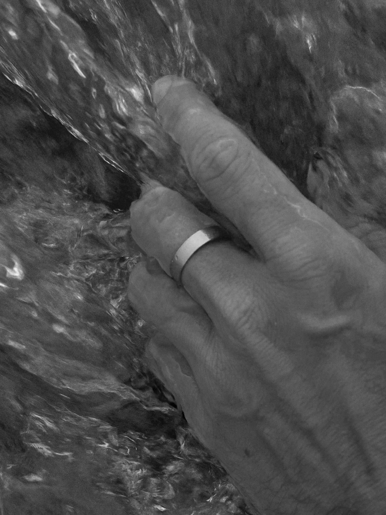 יד של גבר בתוך מים עם טבעת Oyster כסופה בגימור מט – NERO