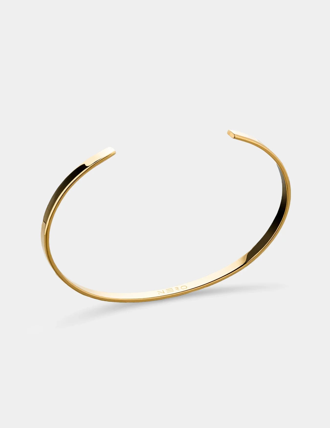צמיד Orca מוזהב בקוטר 3.5 מ״מ על רקע לבן, בעיצוב פתוח עם חריטת NERO פנימית