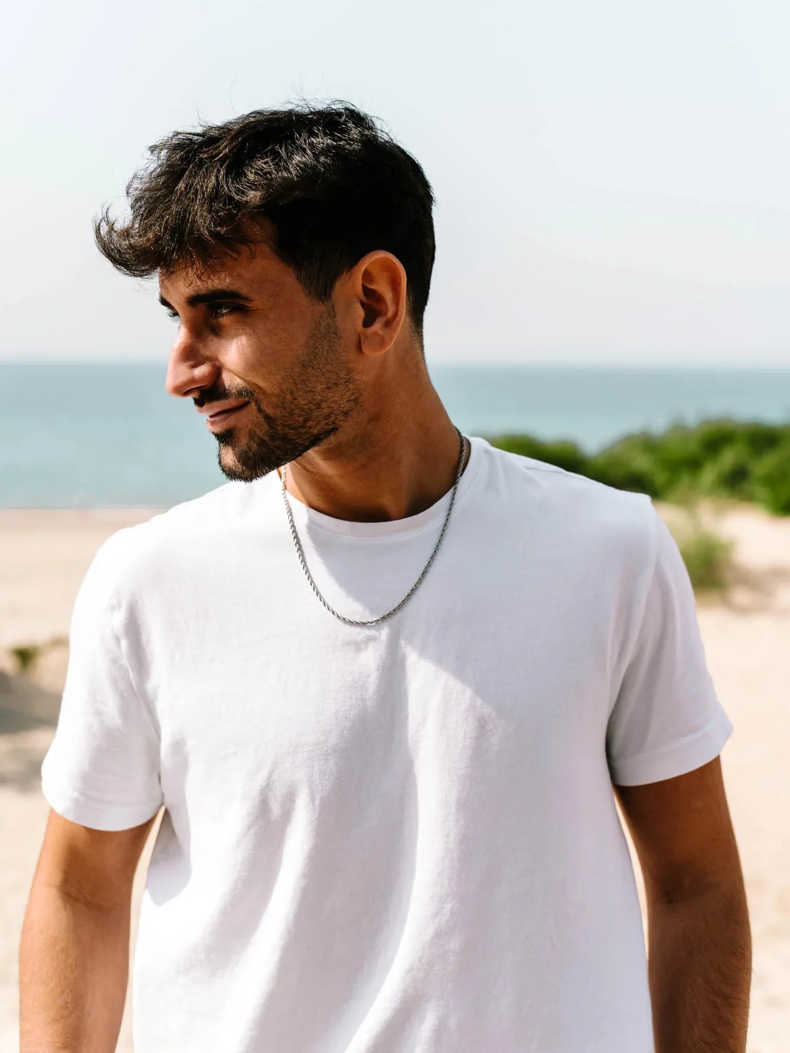 דוגמן לובש שרשרת Eros כסף 3 מ״מ על חולצת טי לבנה בחוף