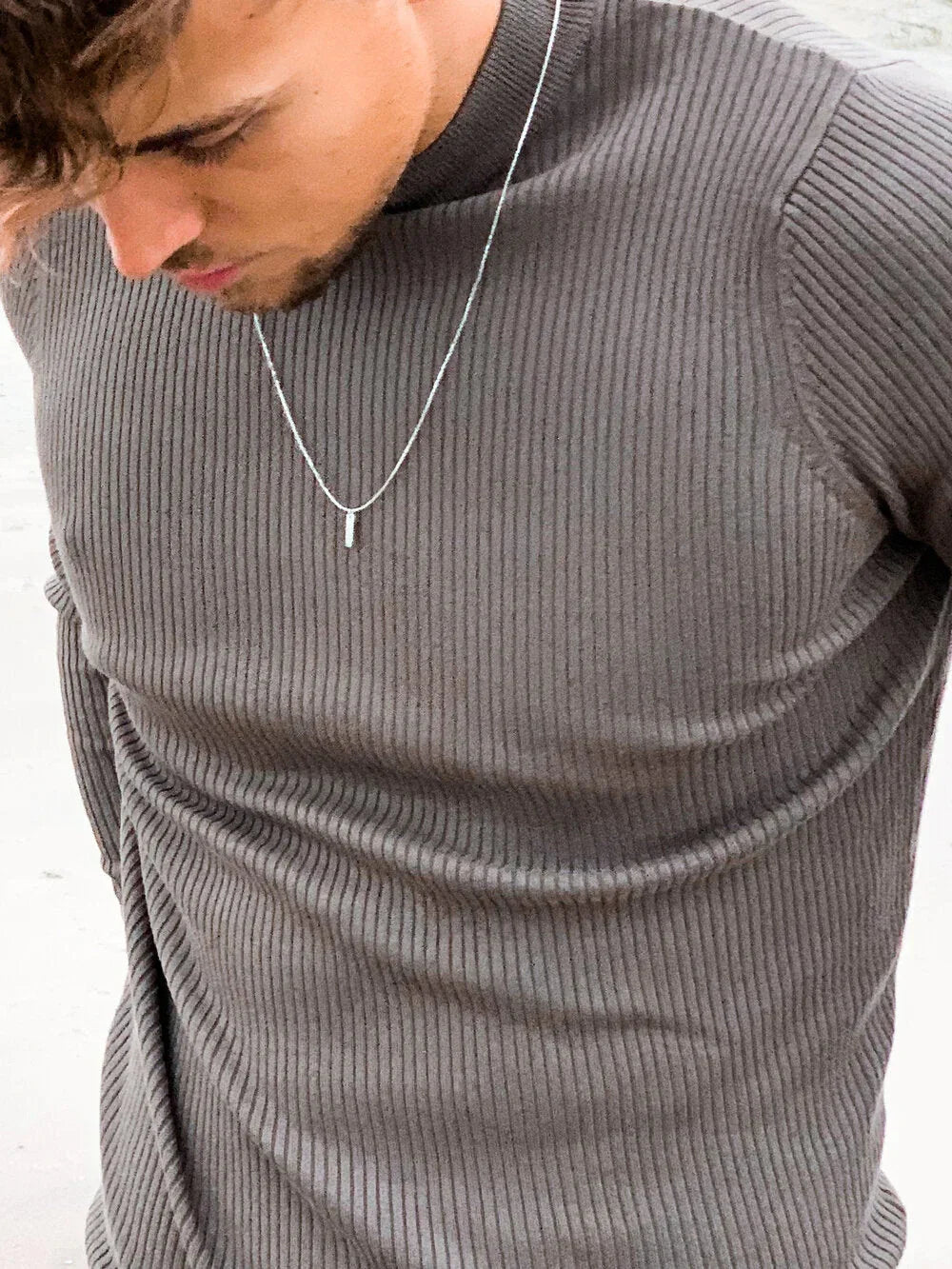 שרשרת עדינה לגבר בצבע כסף על חולצה סרוגה אפורה – דוגמן מביט מטה