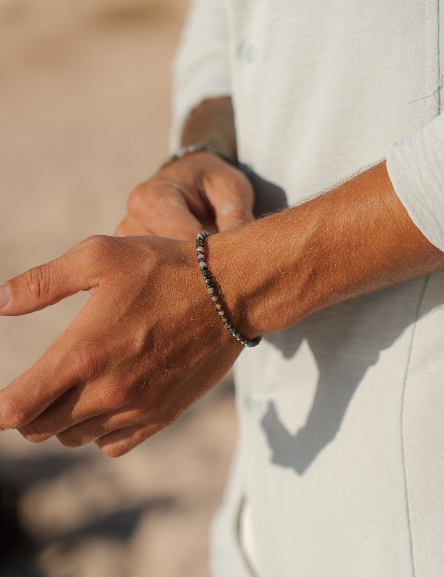 צמיד Tulum לגבר (המטיט ואגט) על פרק יד בחוף, צילום תקריב המדגיש את טקסטורת האבן.