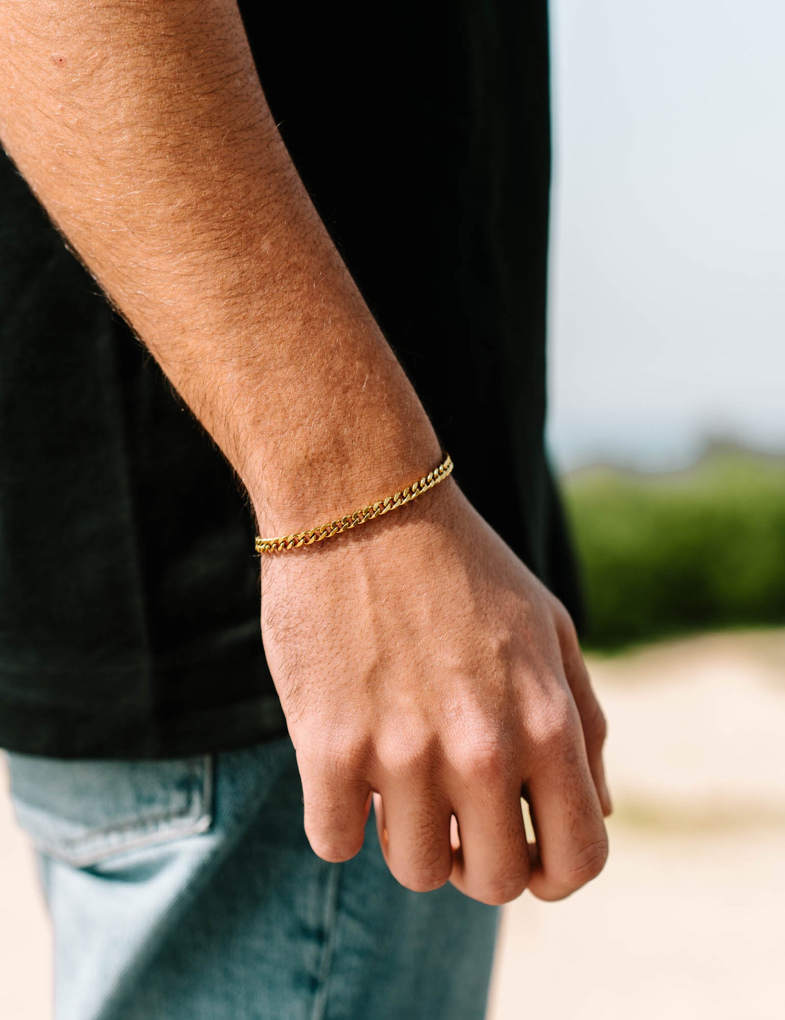 צמיד Zeus מוזהב על פרק יד של גבר ברקע טבע חיצוני