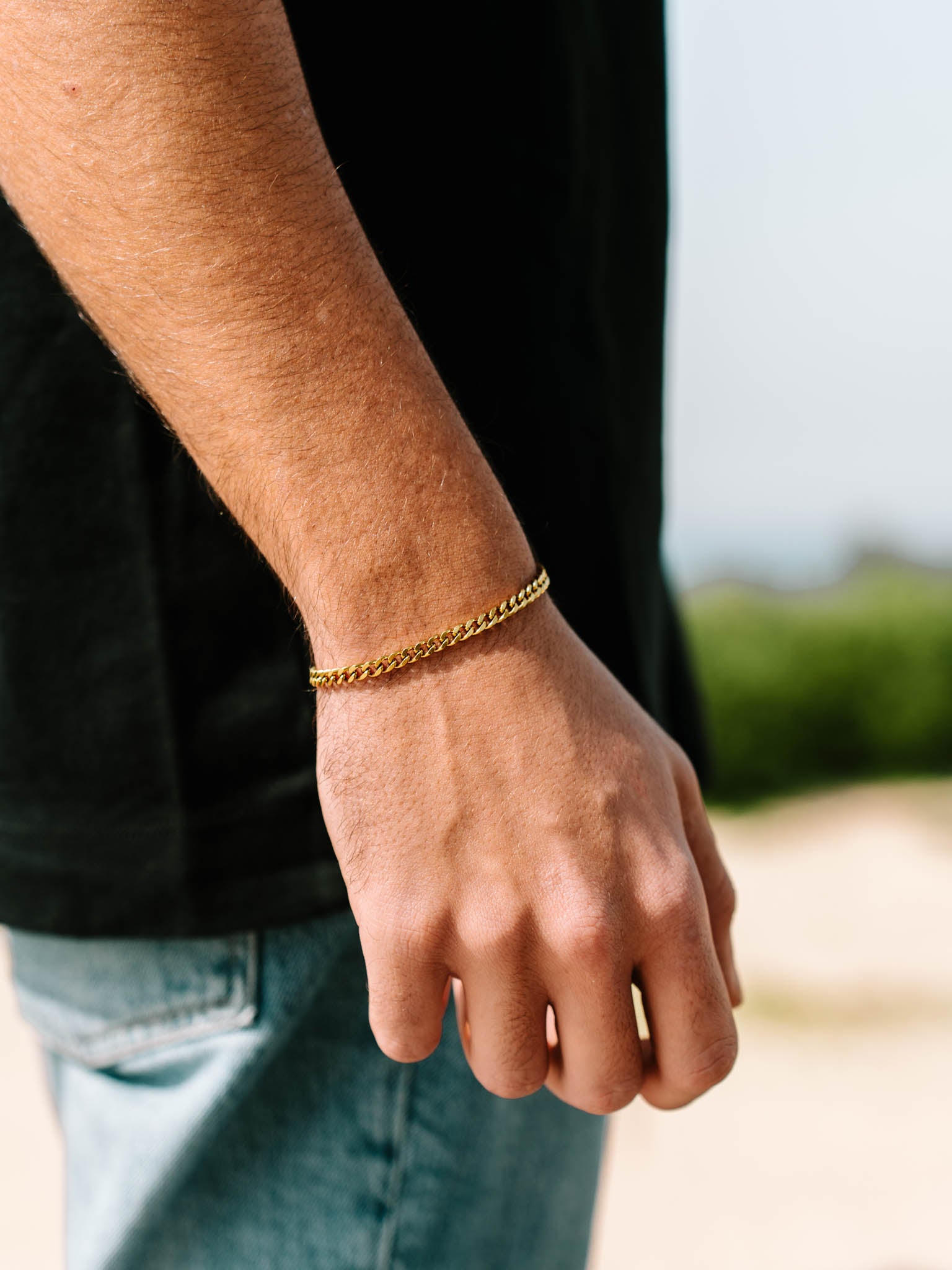 צמיד Zeus מוזהב על פרק יד של גבר ברקע טבע חיצוני