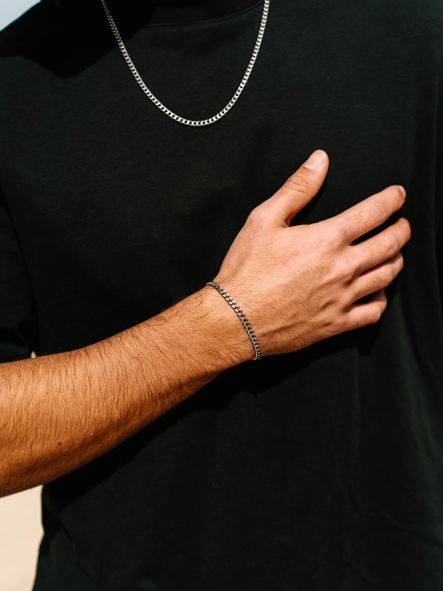 תקריב של צמיד Zeus כסוף על פרק היד, עם רקע חולצה שחורה