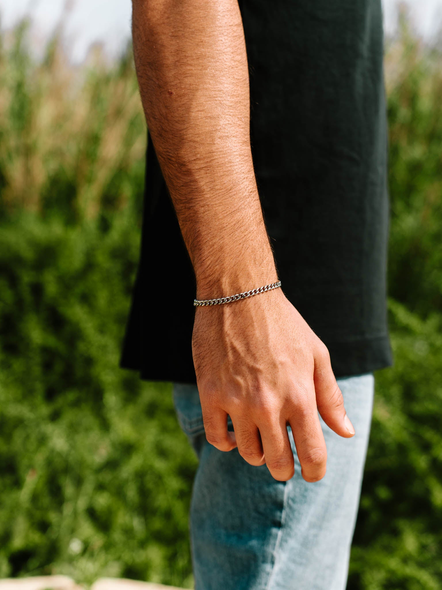 צמיד Zeus כסוף מצדו של פרק היד, ברקע צמחייה ירוקה