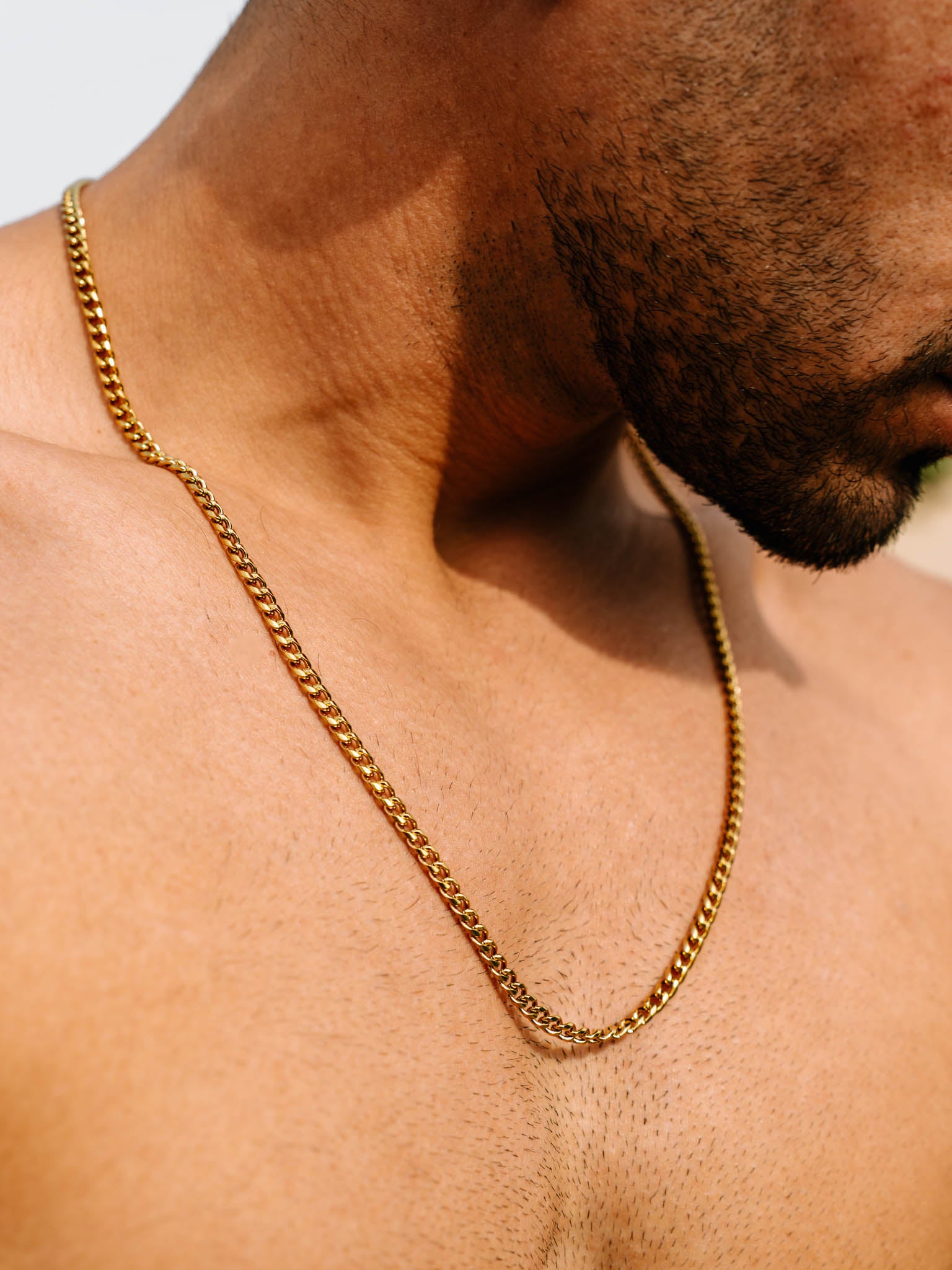 שרשרת Zeus מוזהבת 4 מ״מ על צוואר של גבר, צילום תקריב באור טבעי