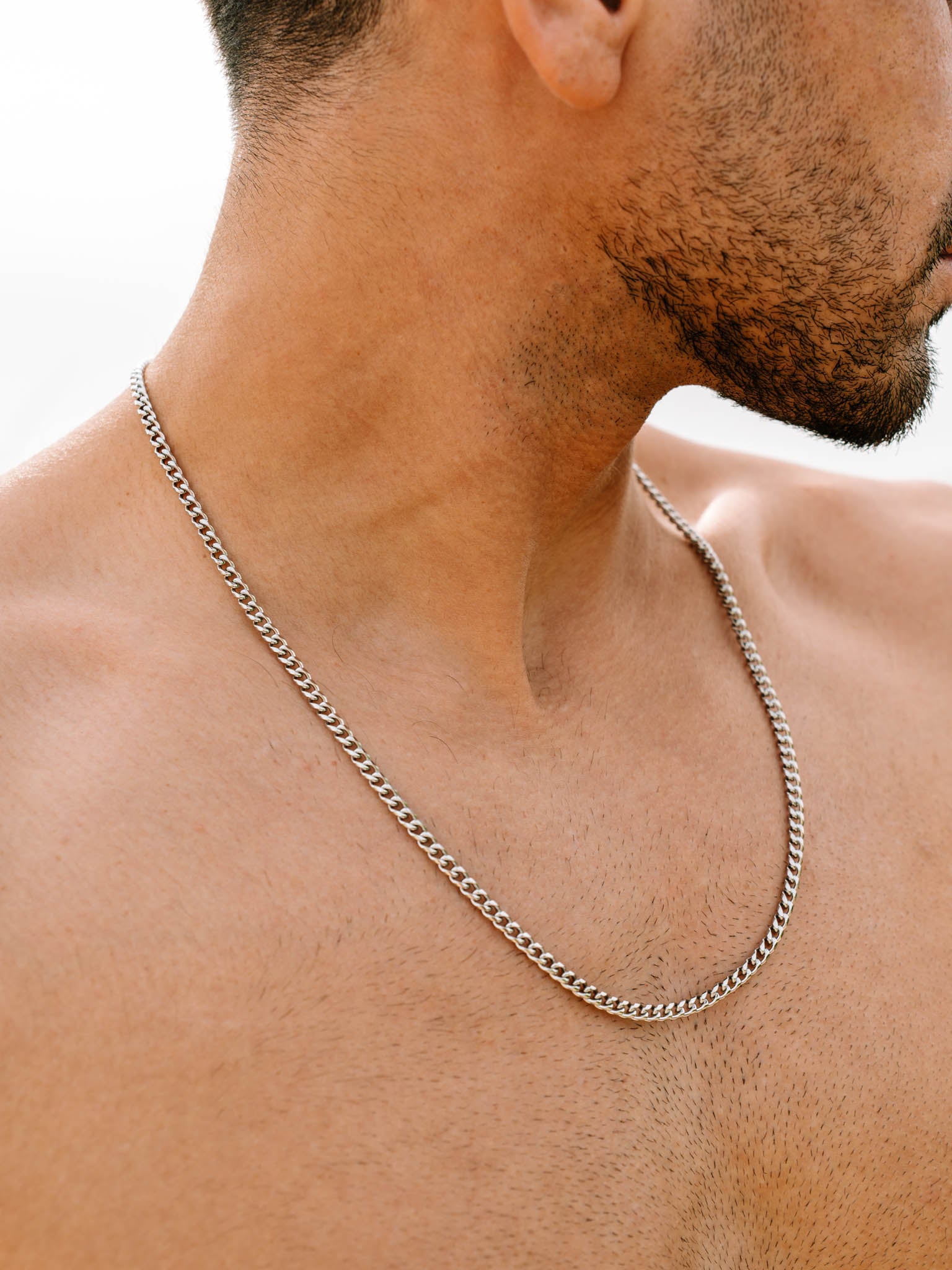 שרשרת Zeus כסופה 4 מ״מ על צוואר גבר ללא חולצה בצילום תקריב